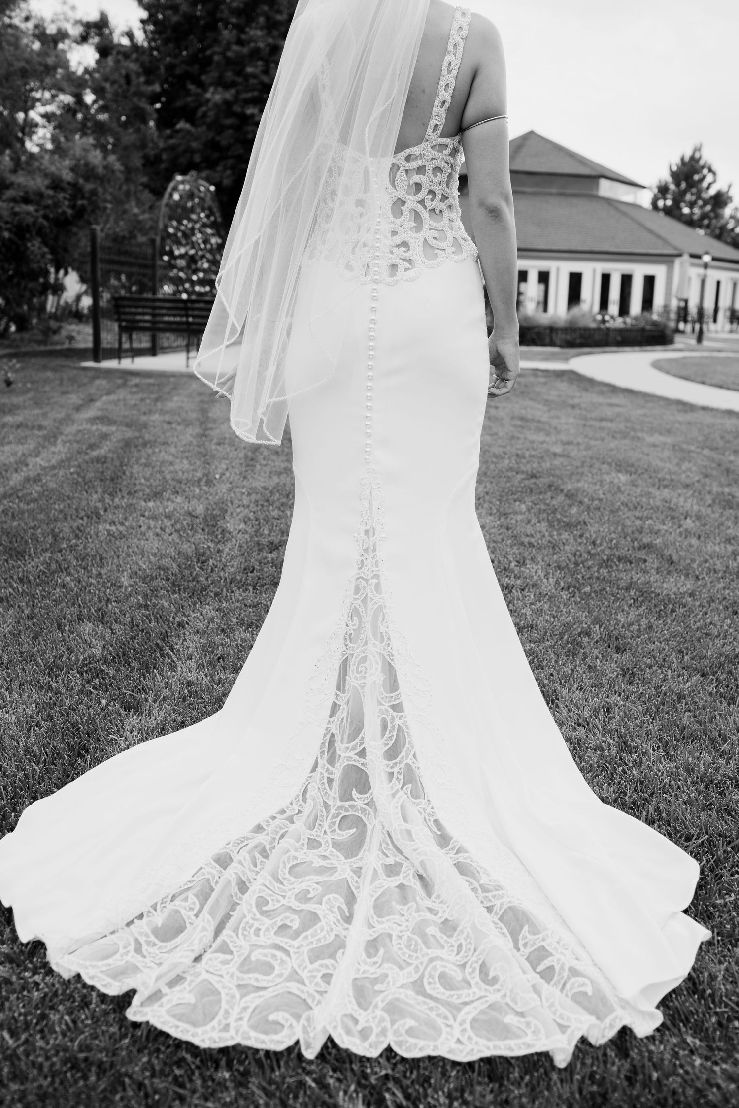 Detail shots of intricate lace wedding dress train on manicured lawn.