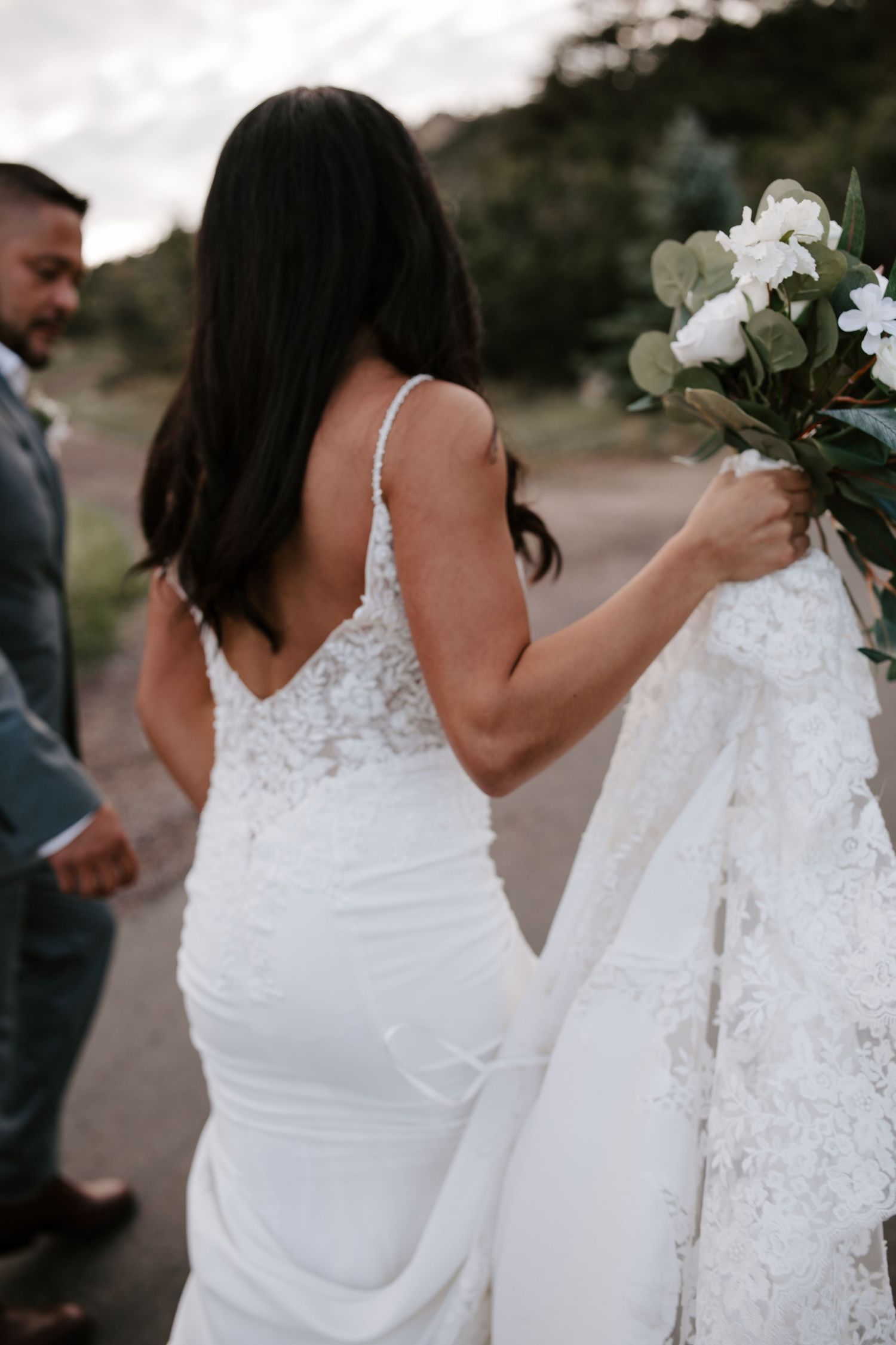 Close-up view of two elegant white wedding dresses with lace details and floral bouquets.