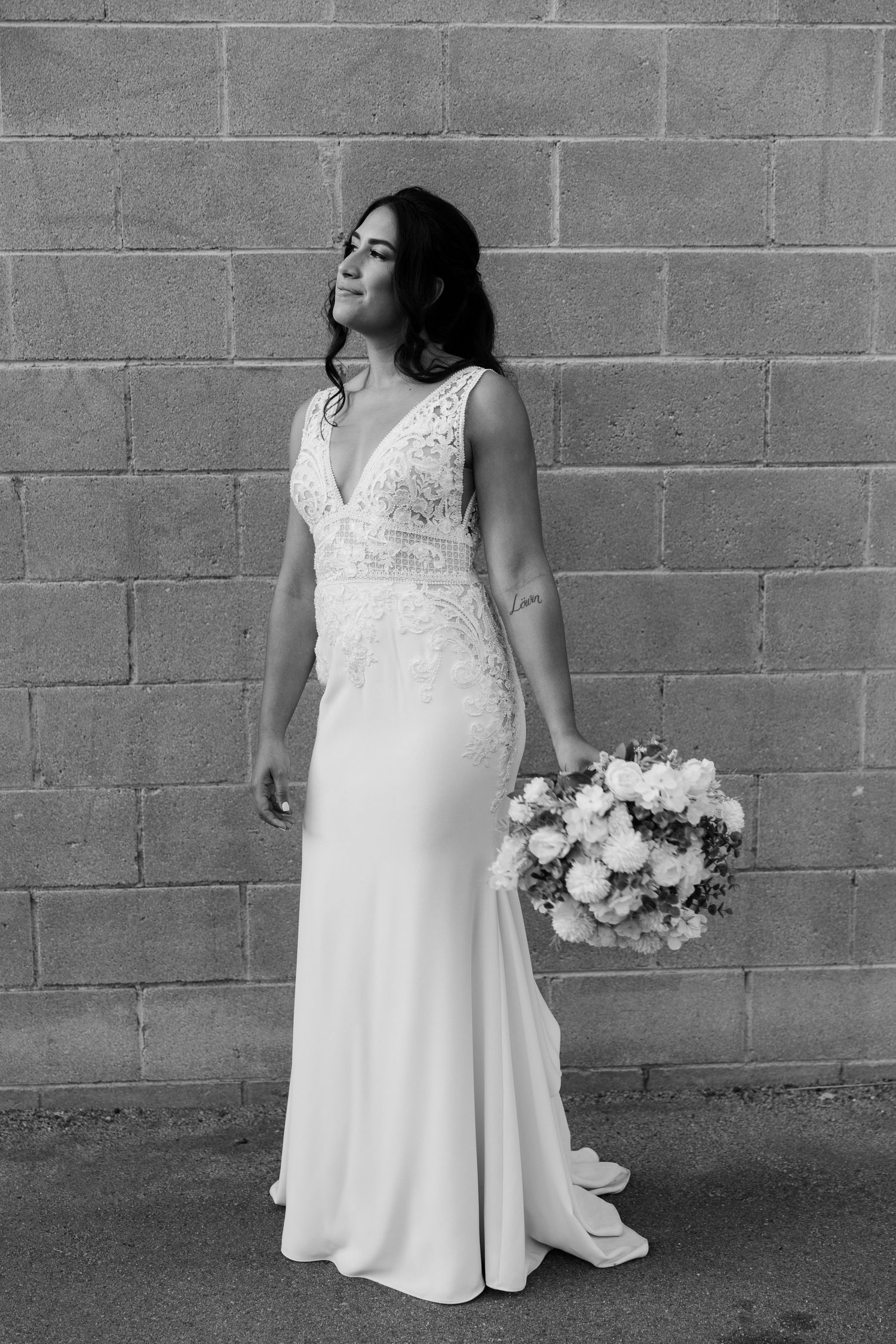Black and white bridal portrait against brick wall with bouquet.