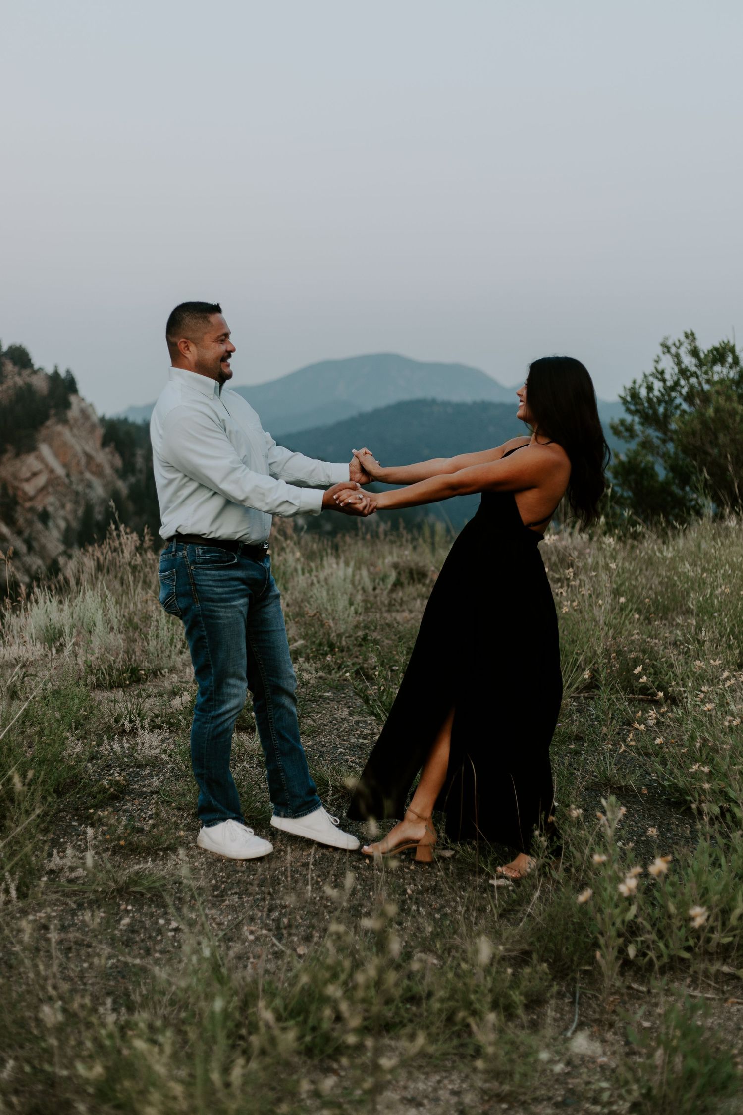 Couple dancing together on mountainside during engagement photoshoot.