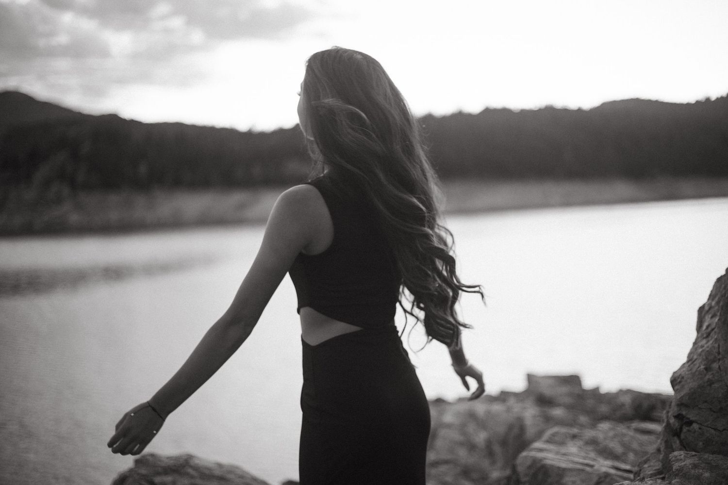 Silhouetted figure stands against a tranquil lake at sunset creating a dreamy atmosphere.