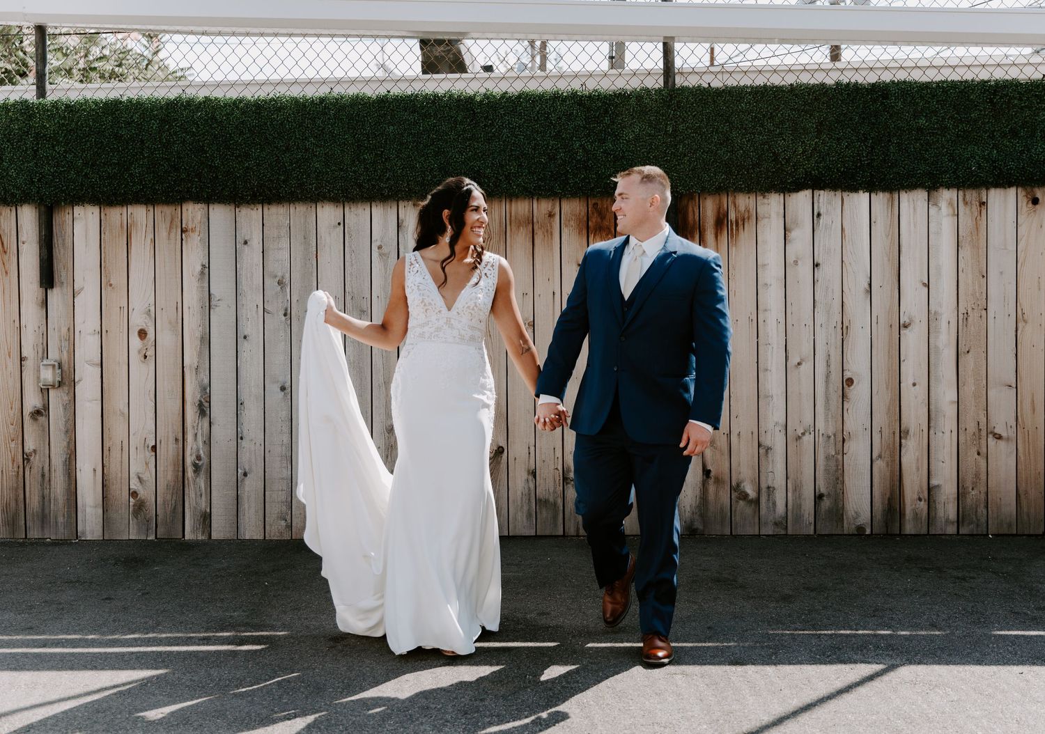 Series showing couple walking together against white wooden fence in bright sunlight.