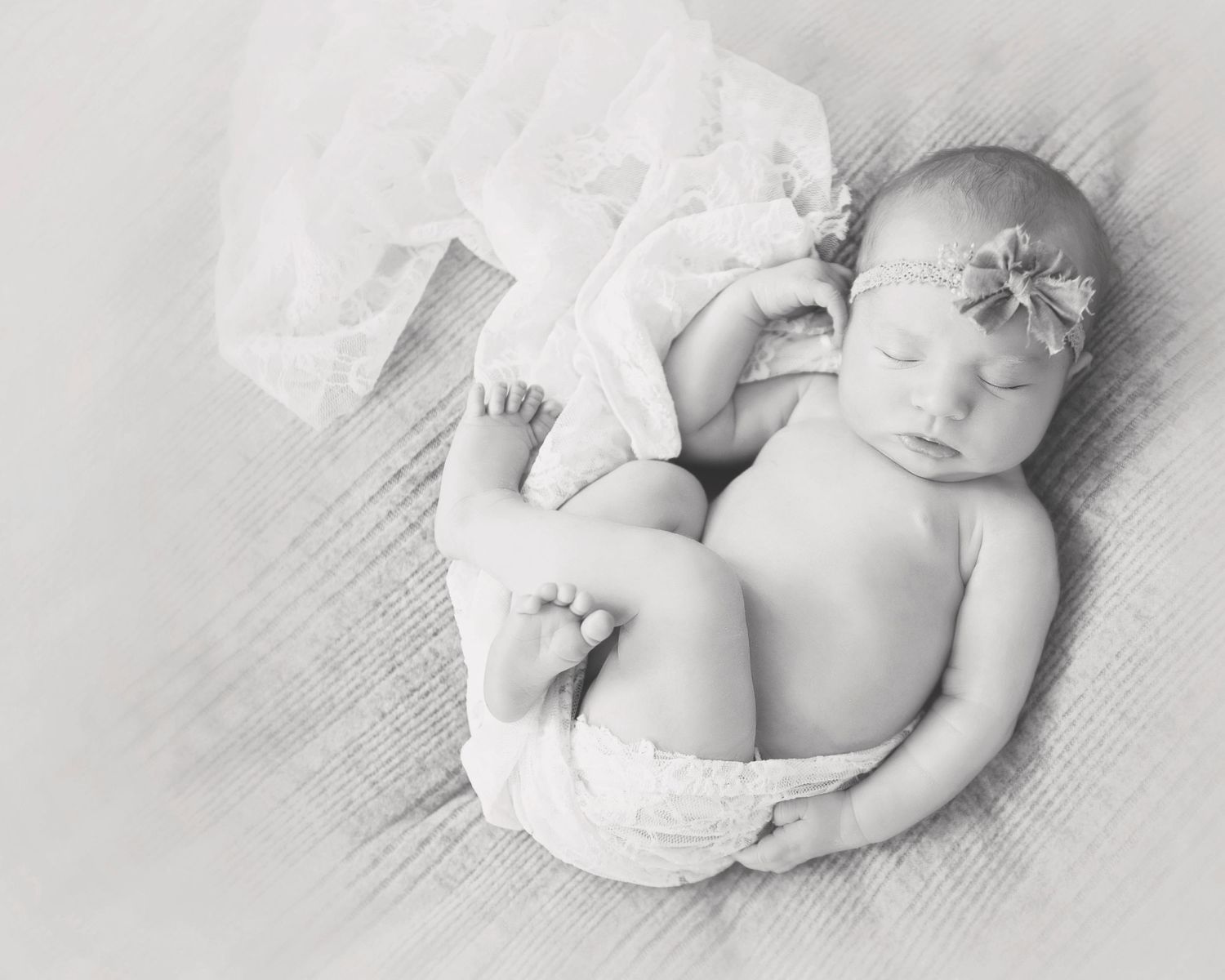 Black and white portrait of peaceful sleeping newborn with floral headband.