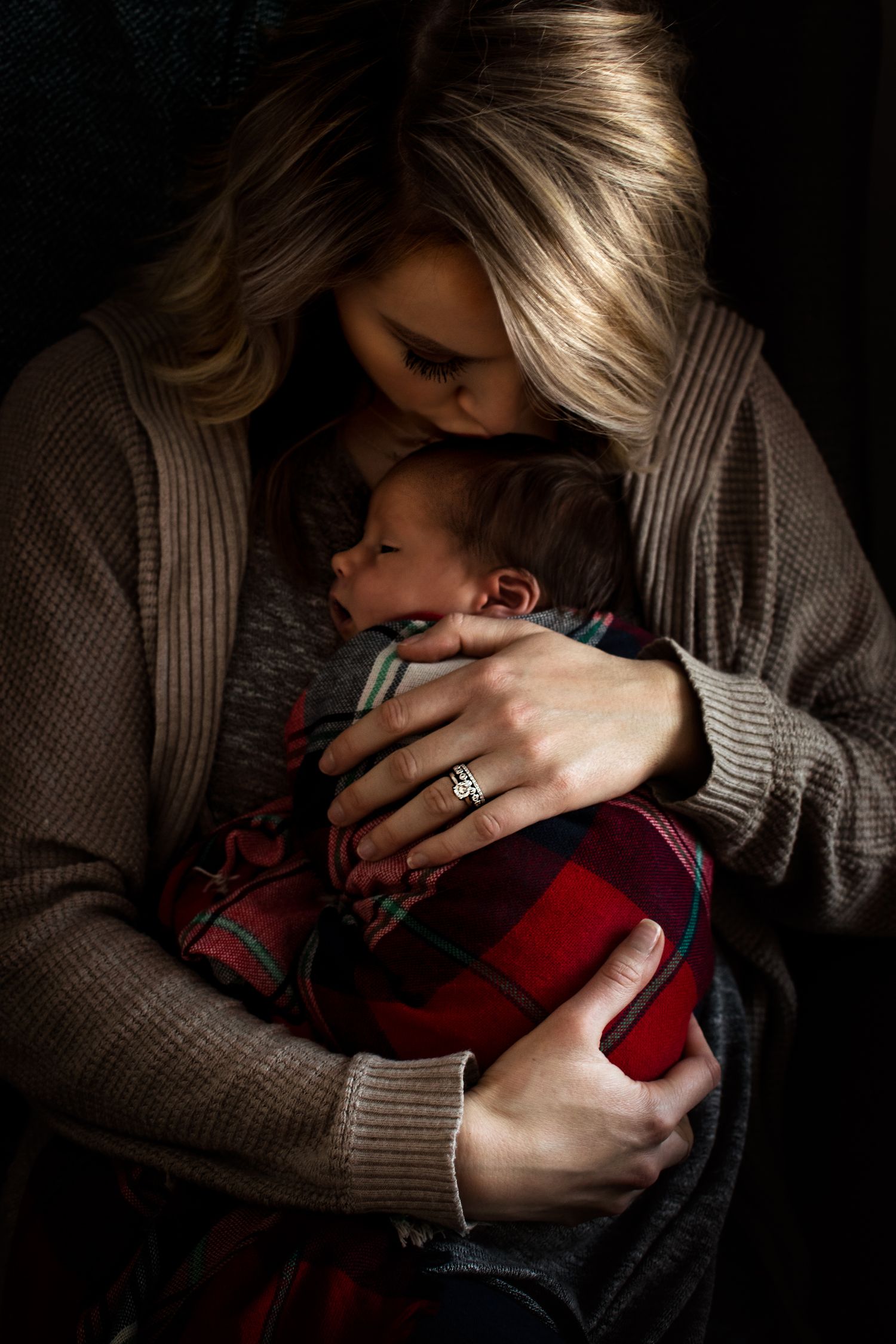 Intimate portrait showing maternal bond in dramatic low-key lighting.