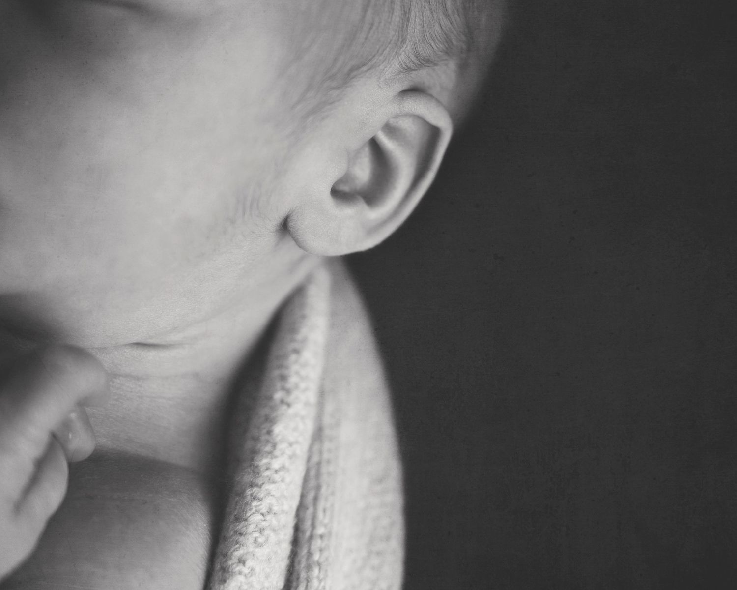 Black and white close-up detail of baby ear and neck.