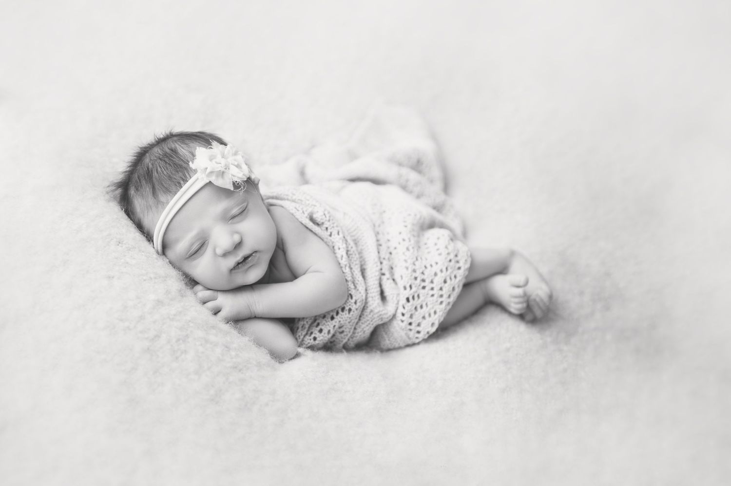 Black and white portrait of sleeping infant wearing delicate lace outfit.