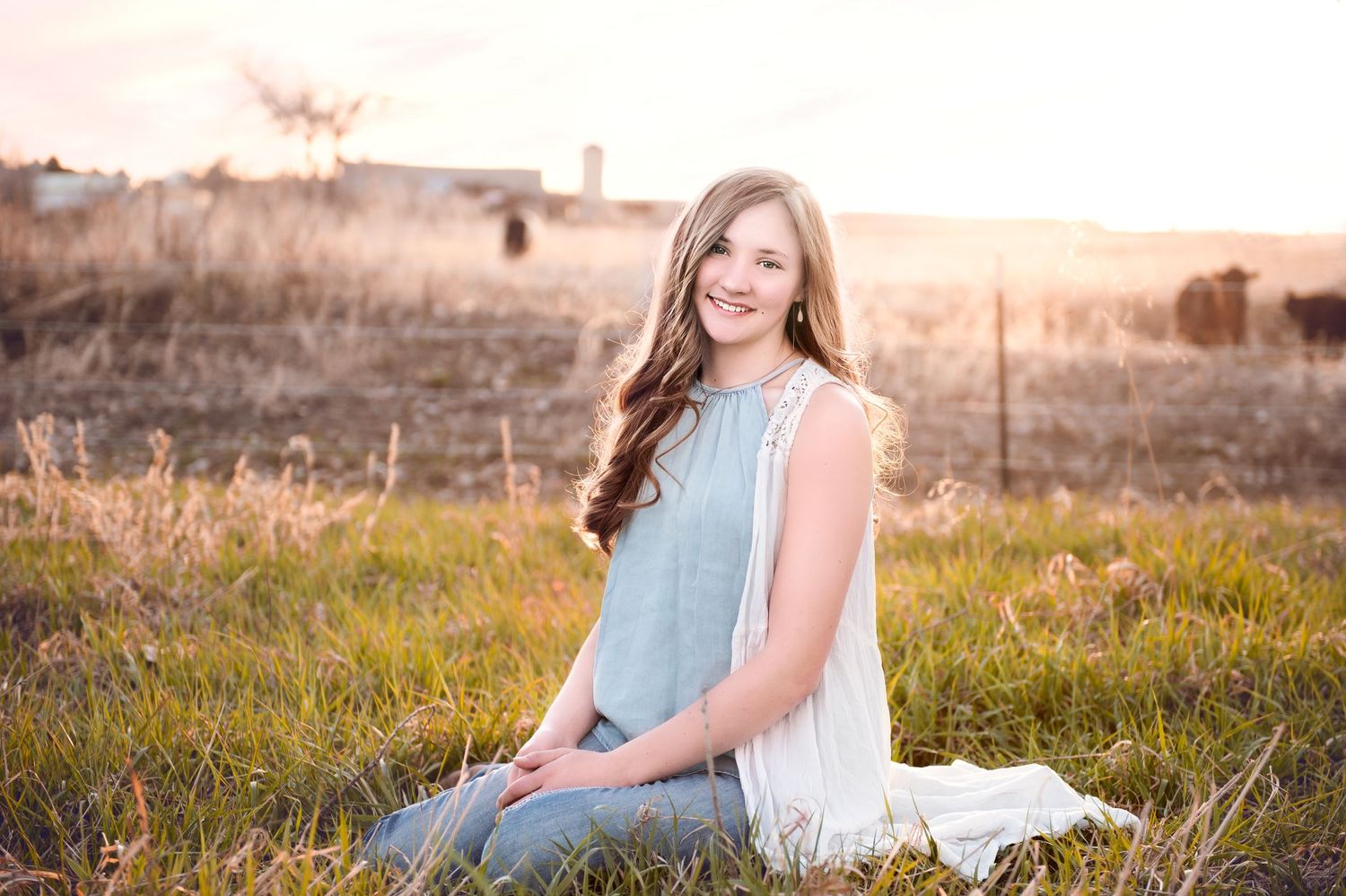 Outdoor portrait in soft blue top against golden sunset light and natural landscape.