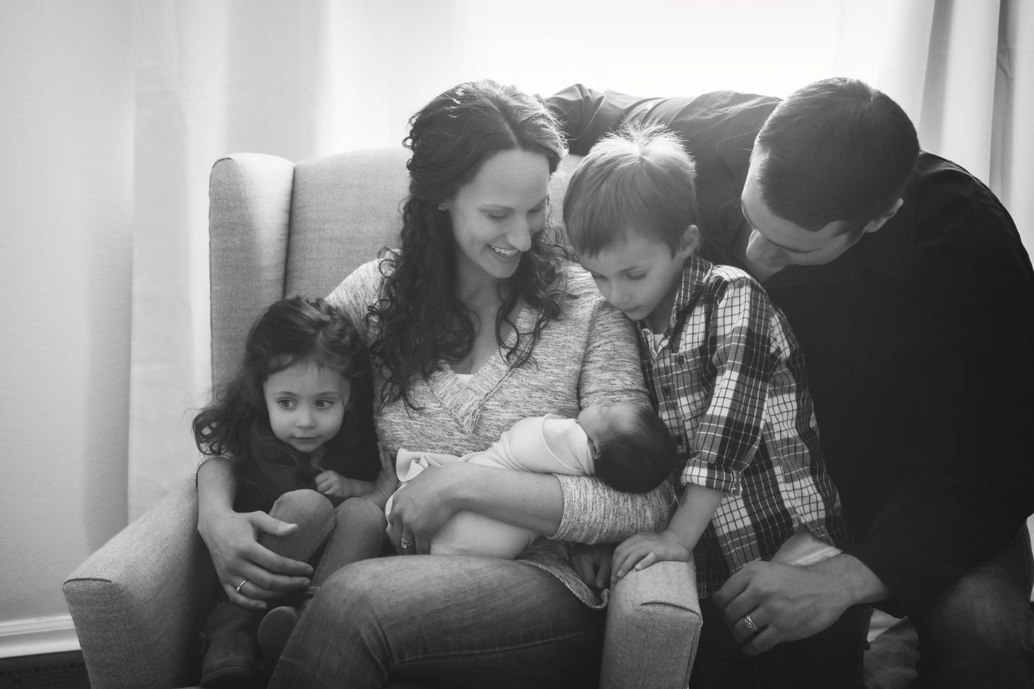 An intimate family moment sharing cuddles on a cozy chair.
