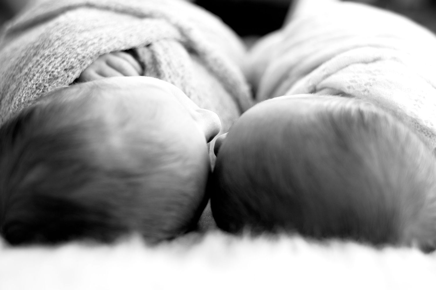 Close-up black and white image of two sleeping infants lying together.