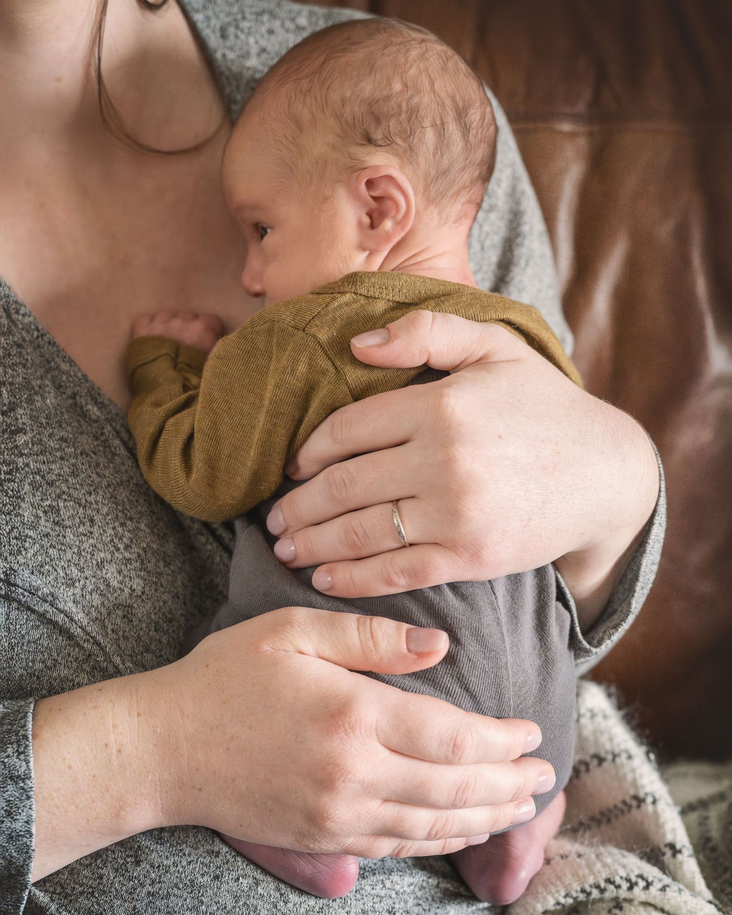Close-up of tender moment with baby wearing mustard sweater being held gently.