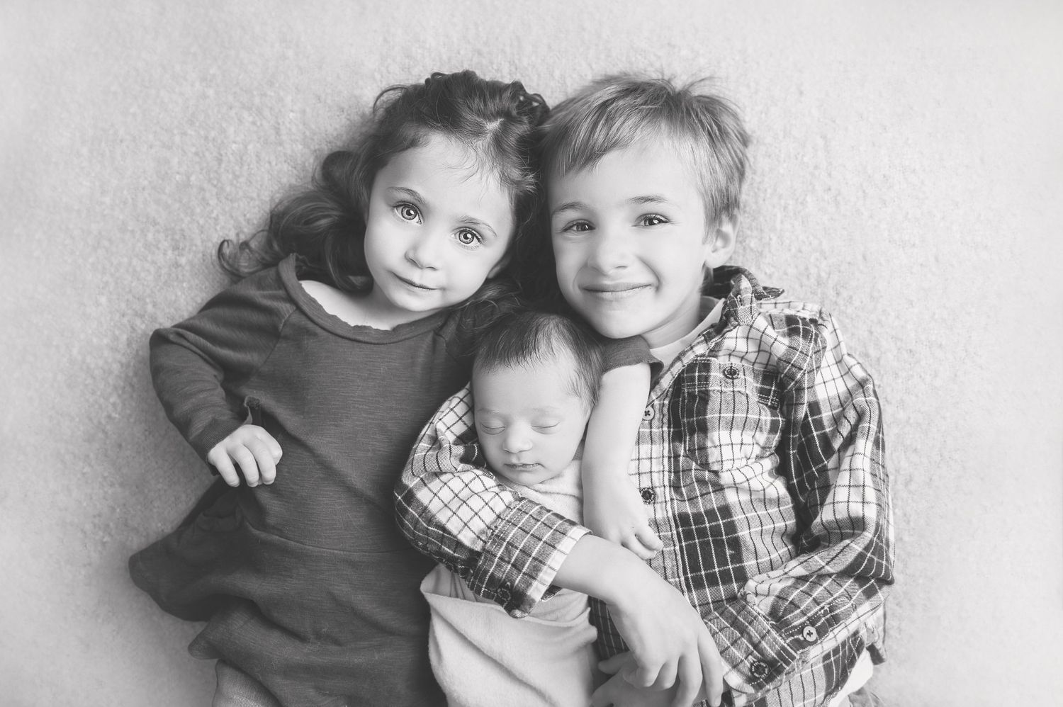 Vintage style black and white portrait of three young siblings together.