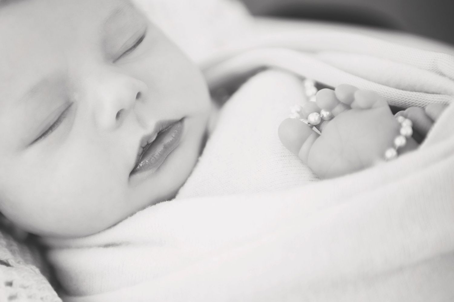 Close-up black and white portrait of a sleeping newborn baby's face.