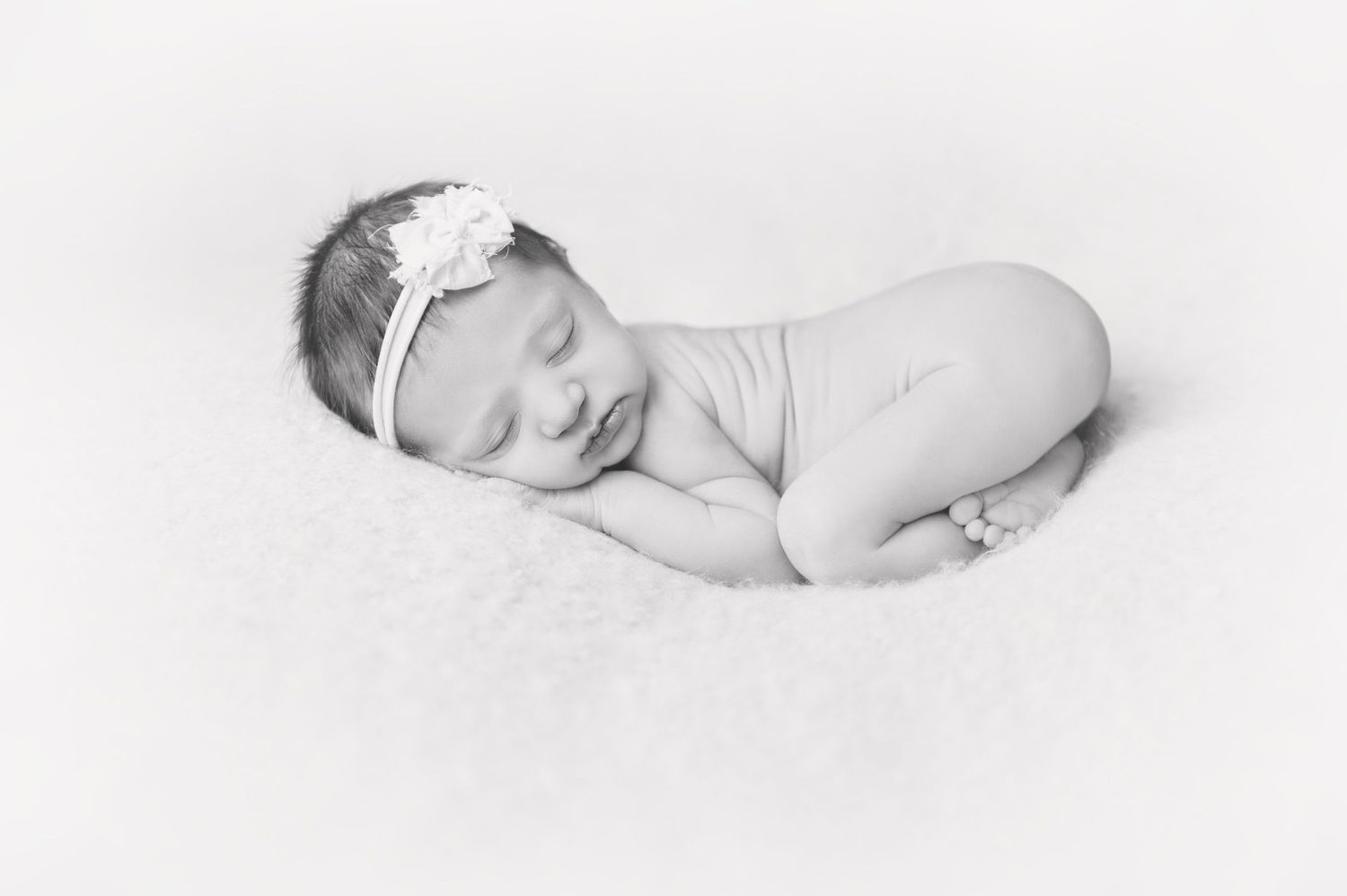 Black and white portrait of sleeping newborn with delicate white headband.