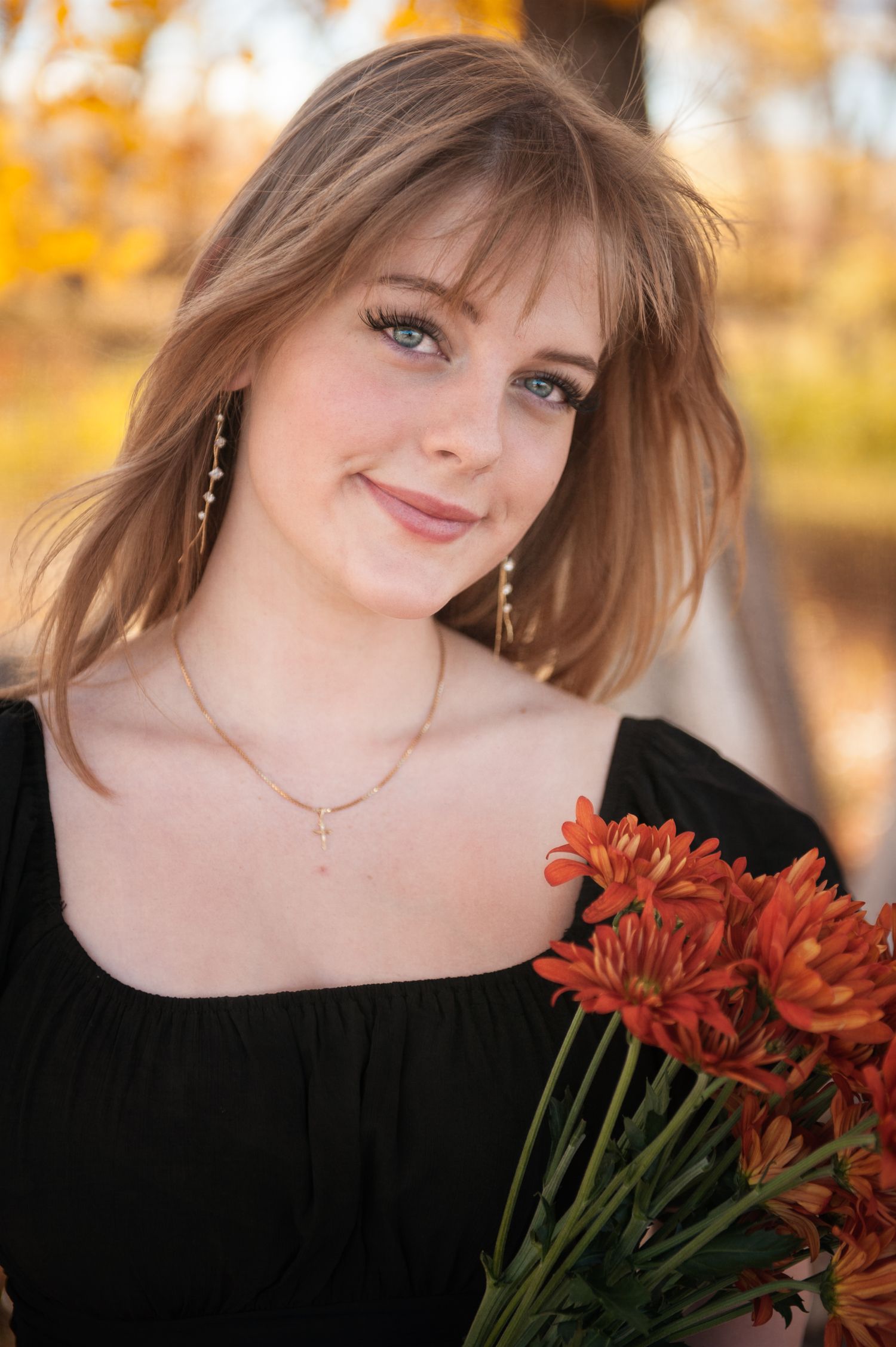 Portrait with orange flowers against autumn foliage background.