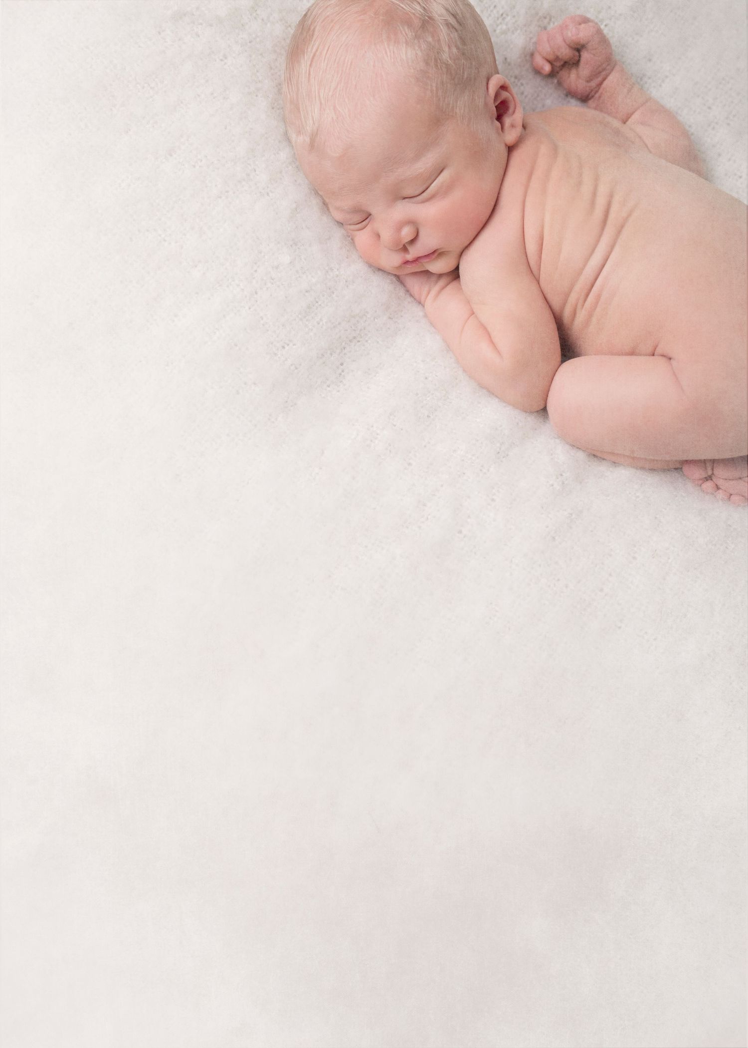 A sleeping newborn lies on soft white textured fabric in a minimalist portrait setting.