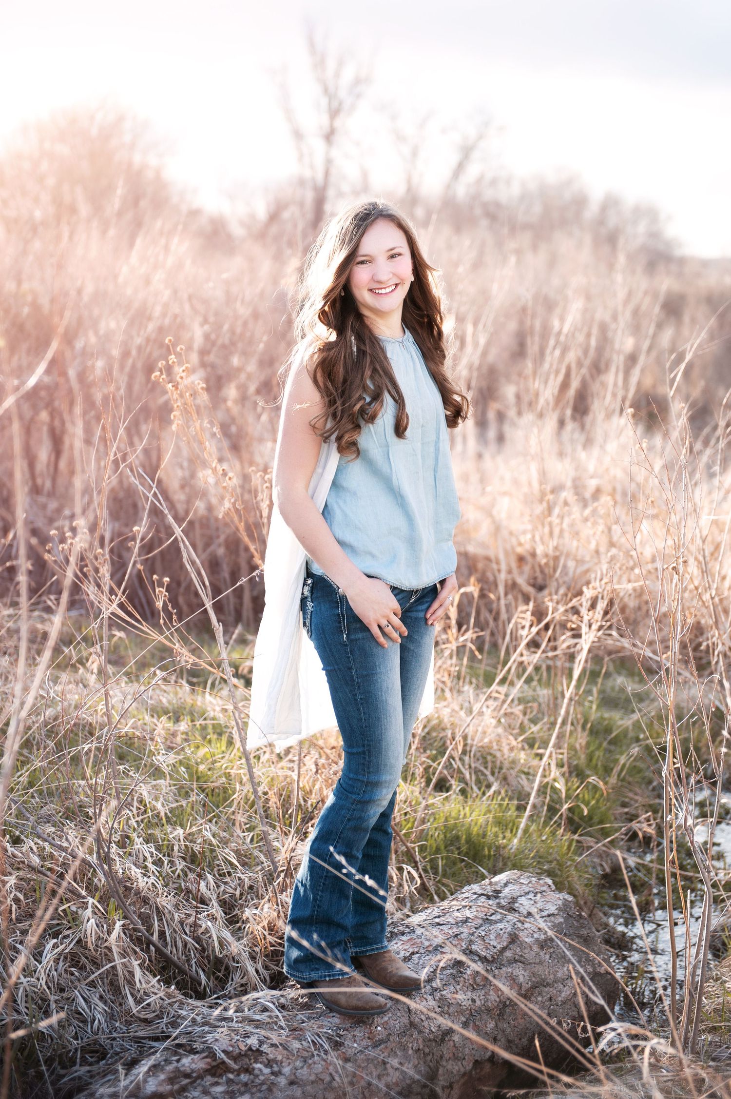 Casual outdoor portrait in blue top and jeans against natural winter landscape.
