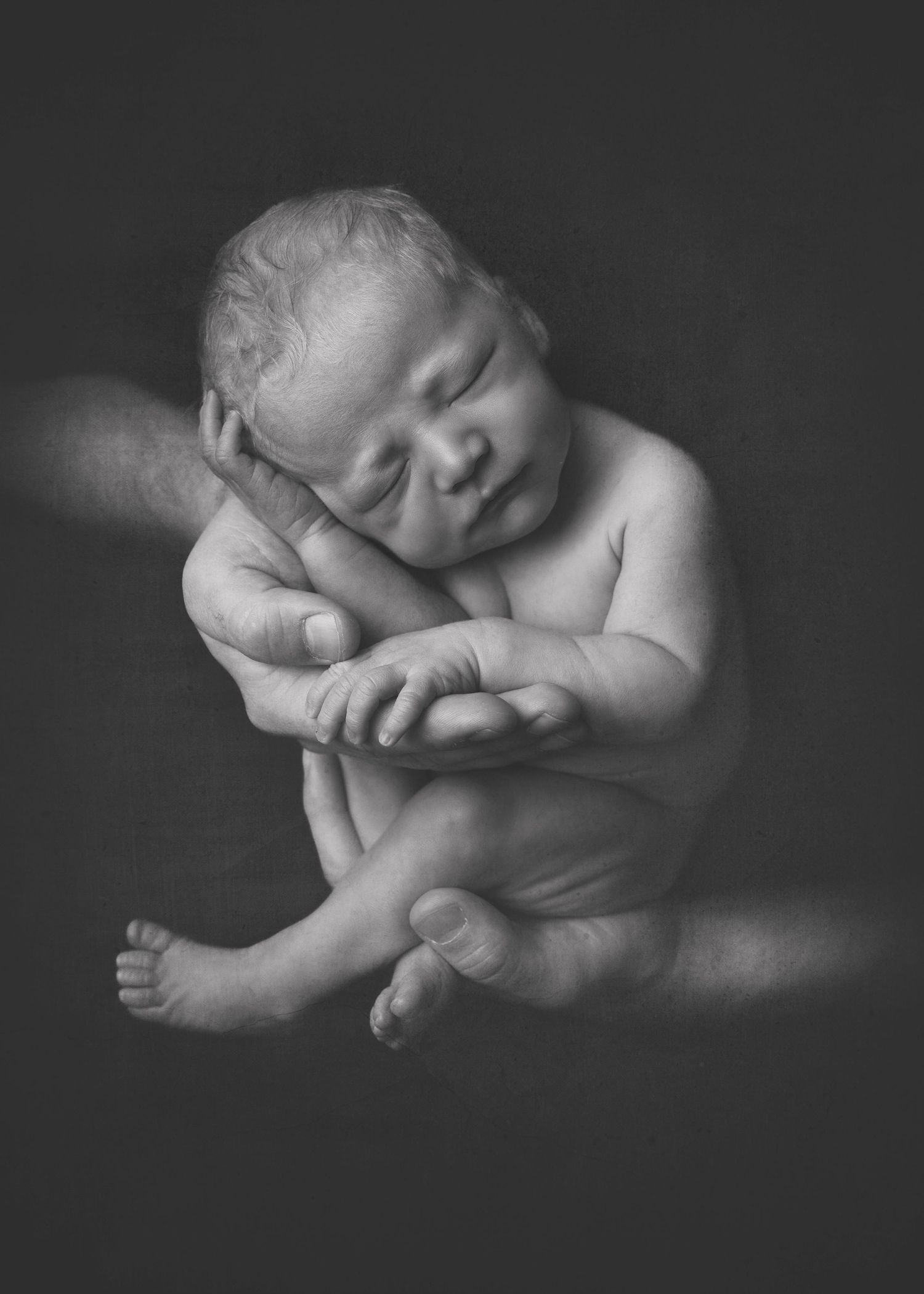 A series of monochromatic artistic photographs showing peaceful sleeping newborn babies in gentle poses against dark backgrounds.