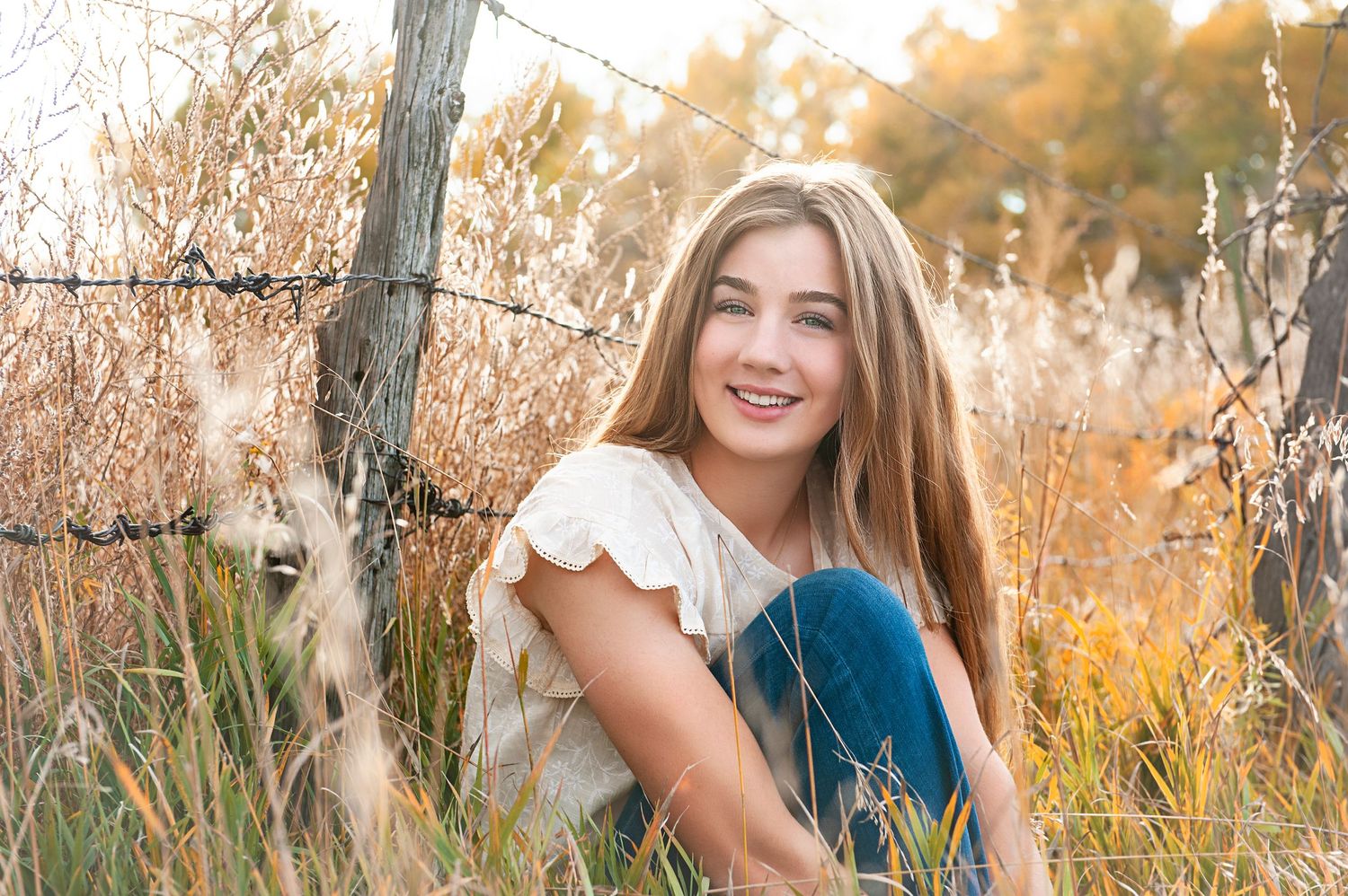 Casual outdoor portrait in autumn field with barbed wire fence.