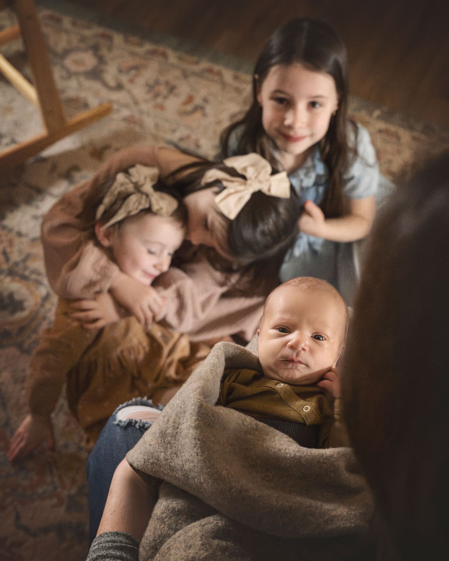 Overhead view of siblings sharing intimate family moment on patterned rug.