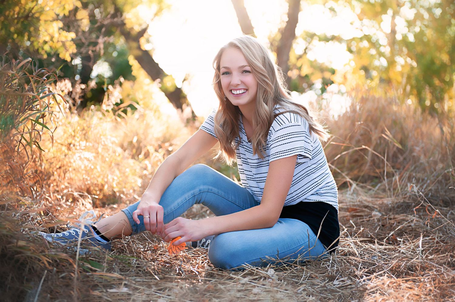 Casual outdoor portrait sitting in golden grass during sunset.