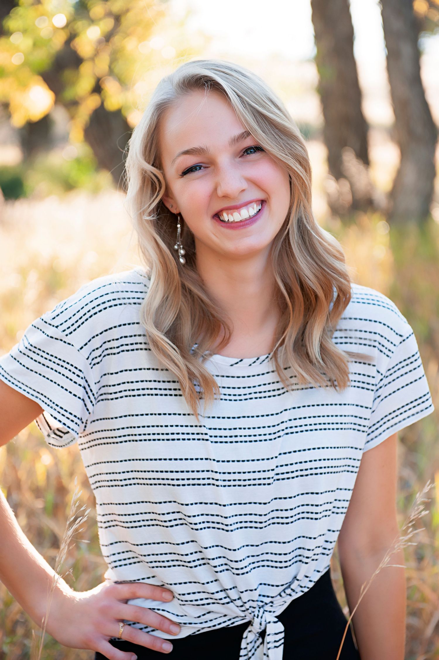 Portrait in black and white striped top with tied front against autumn background.