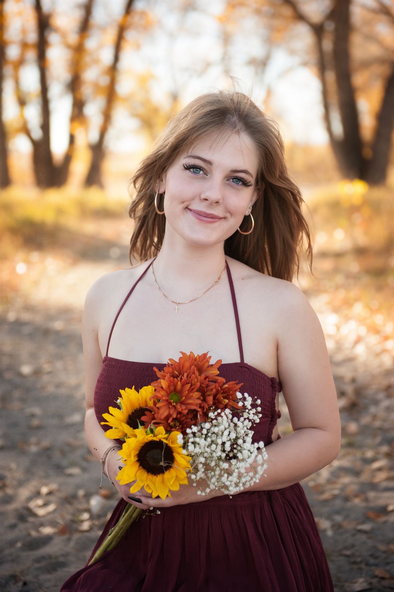 Portrait with sunflowers and orange flowers in golden autumn setting.