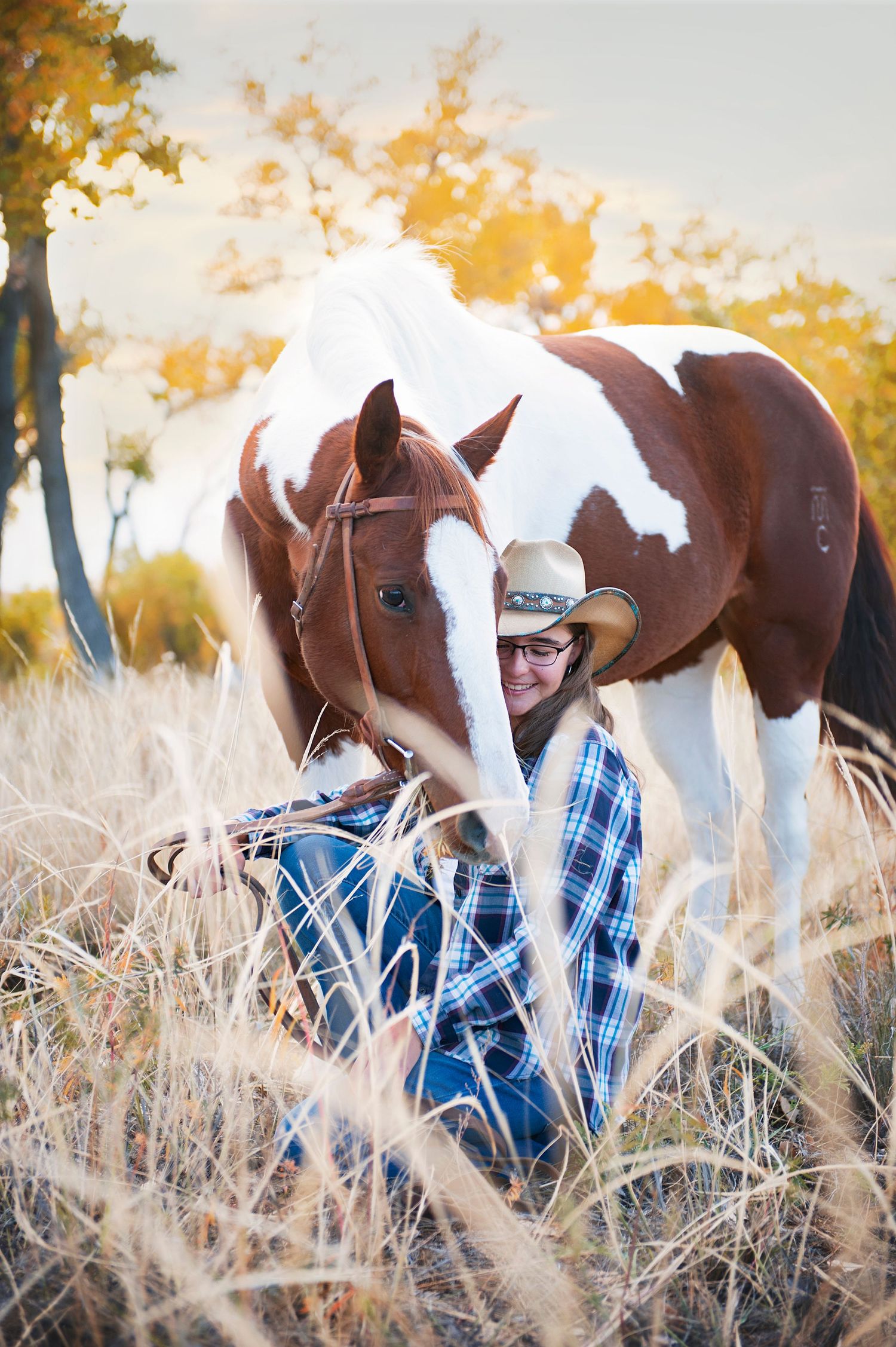 Playful pose with paint horse in tall grass during golden hour.