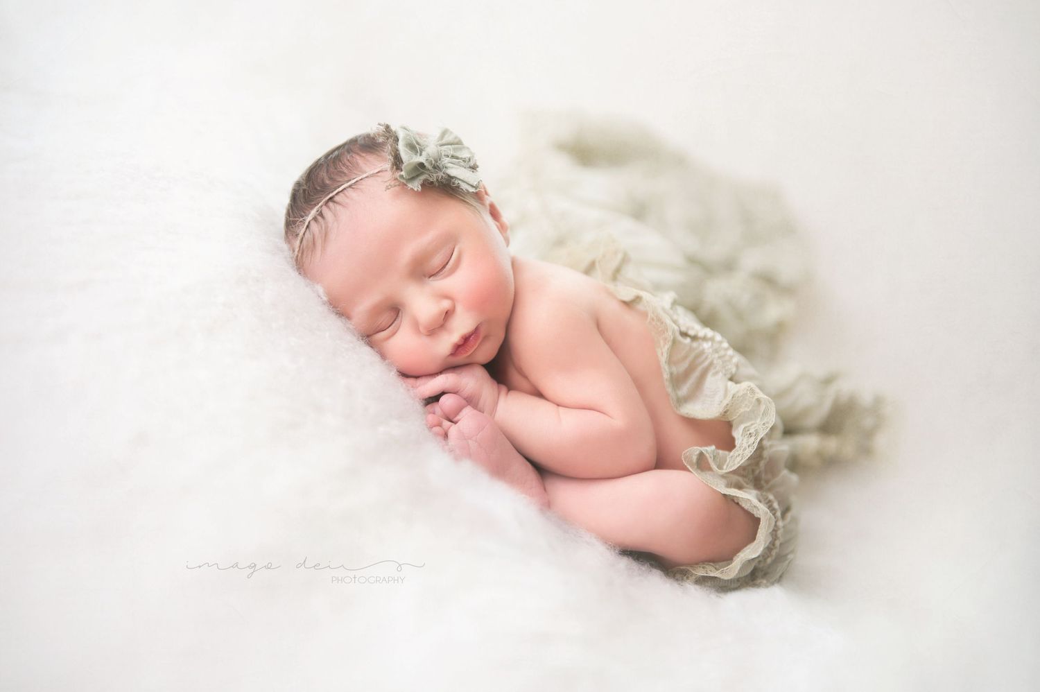 Sleeping newborn baby wrapped in soft white tulle fabric on white background.
