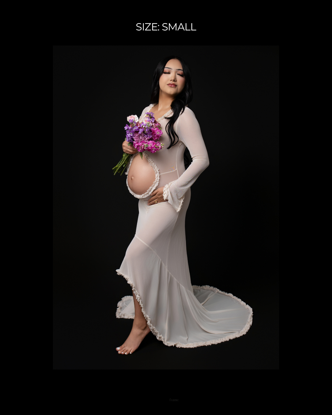 Pregnant woman in white sheer maternity gown holding purple flowers, size small, studio photo on black background.