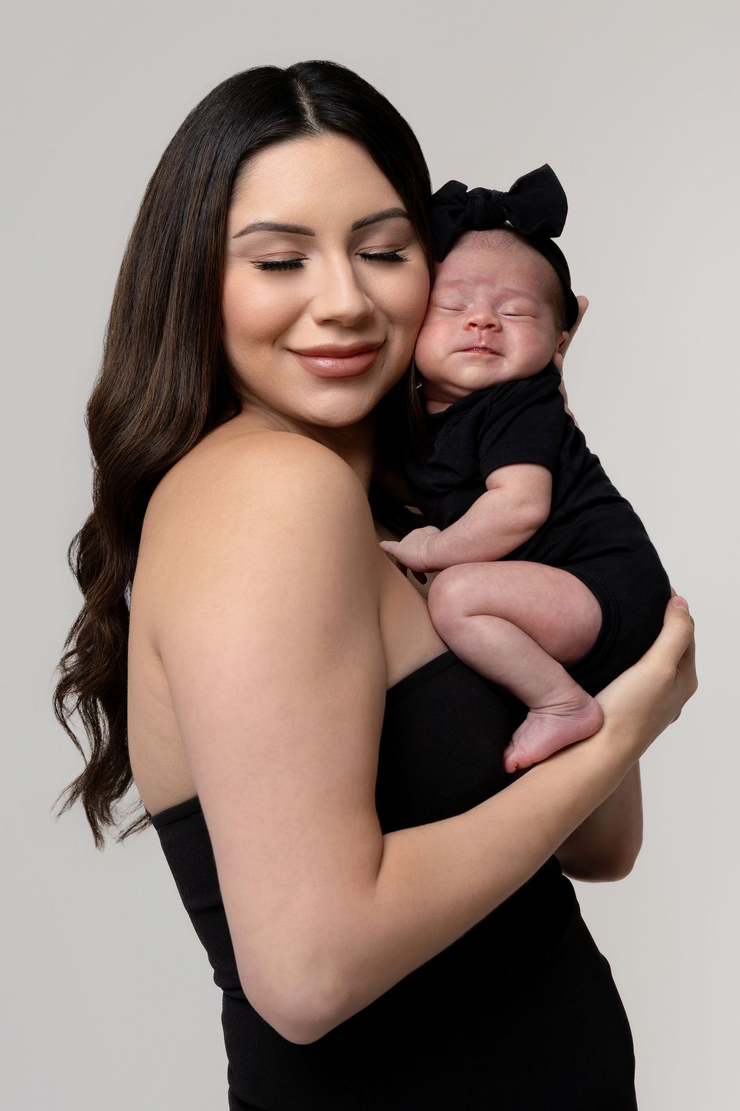 A series of intimate photos showing a woman in a black top holding and cuddling a sleeping newborn baby.