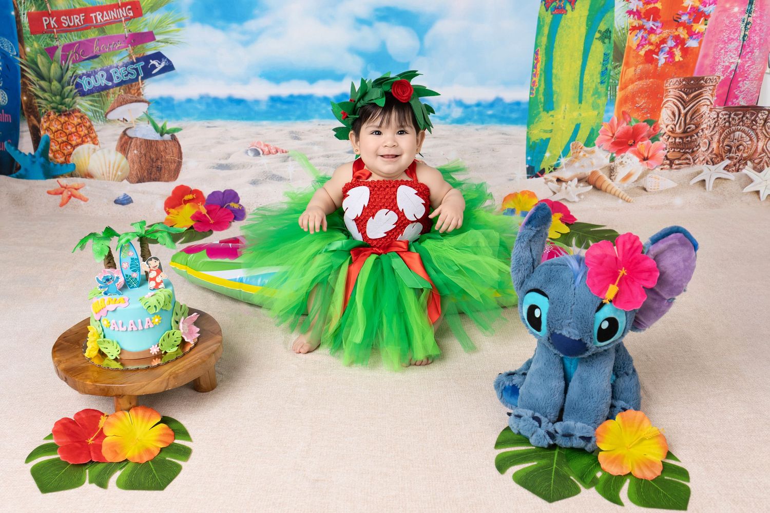 A collection of Hawaiian-themed party decorations featuring Stitch plush toys, grass skirts, and tropical flowers.