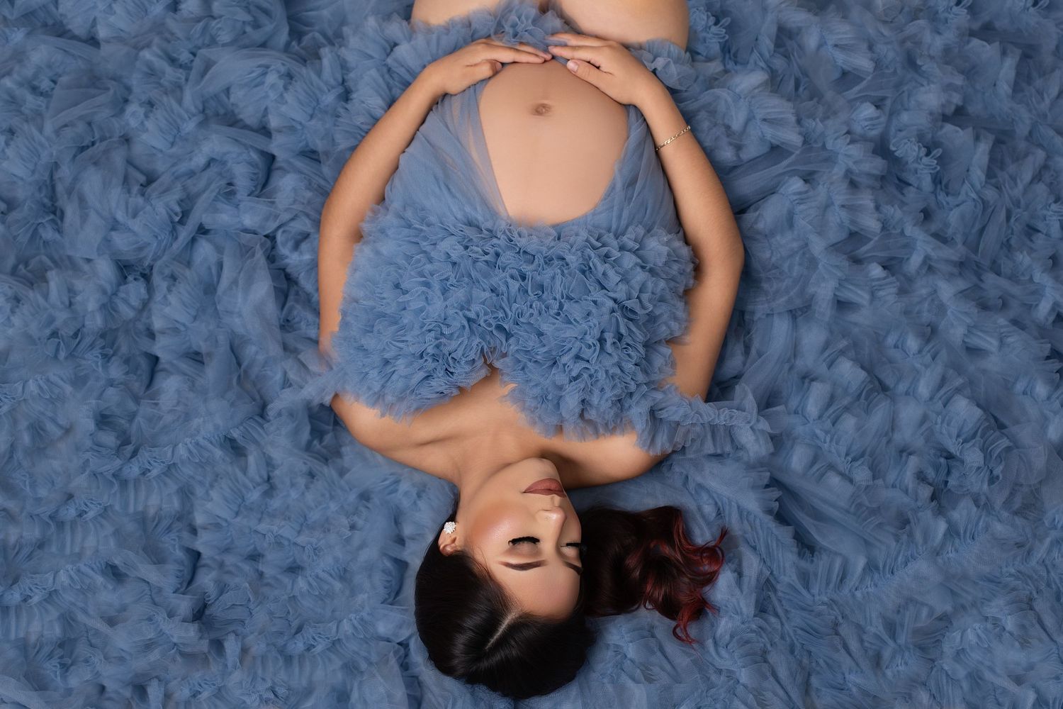 Overhead view of a person lying on plush blue carpet wearing a matching blue dress.