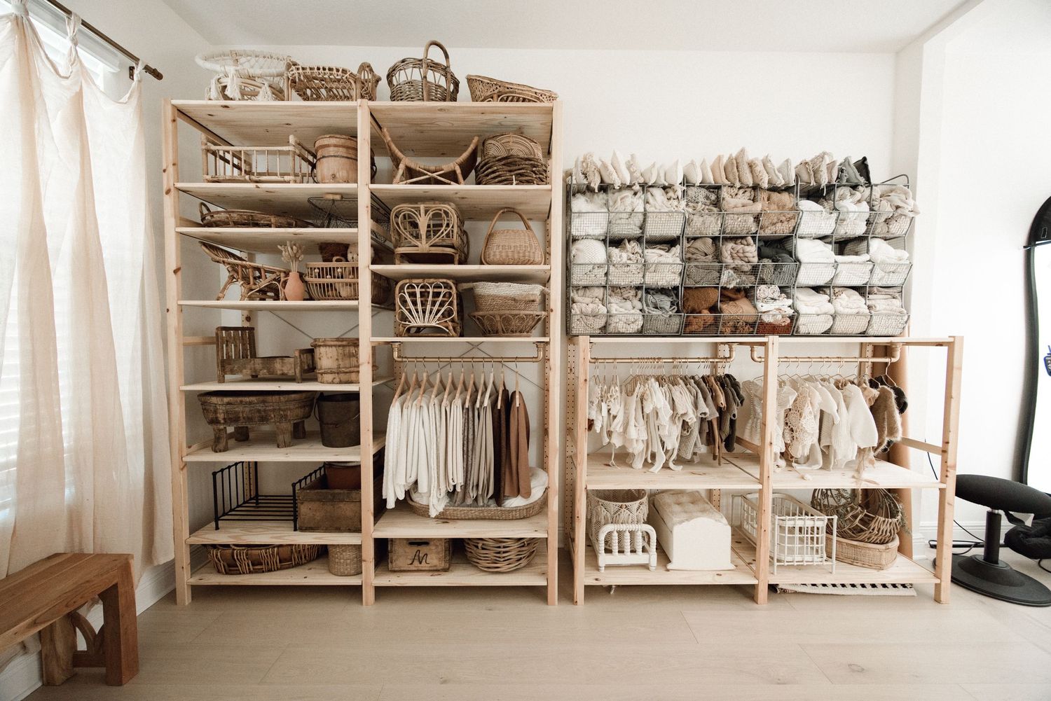 Organized newborn photography studio with neutral props and shelving displaying blankets and accessories.
