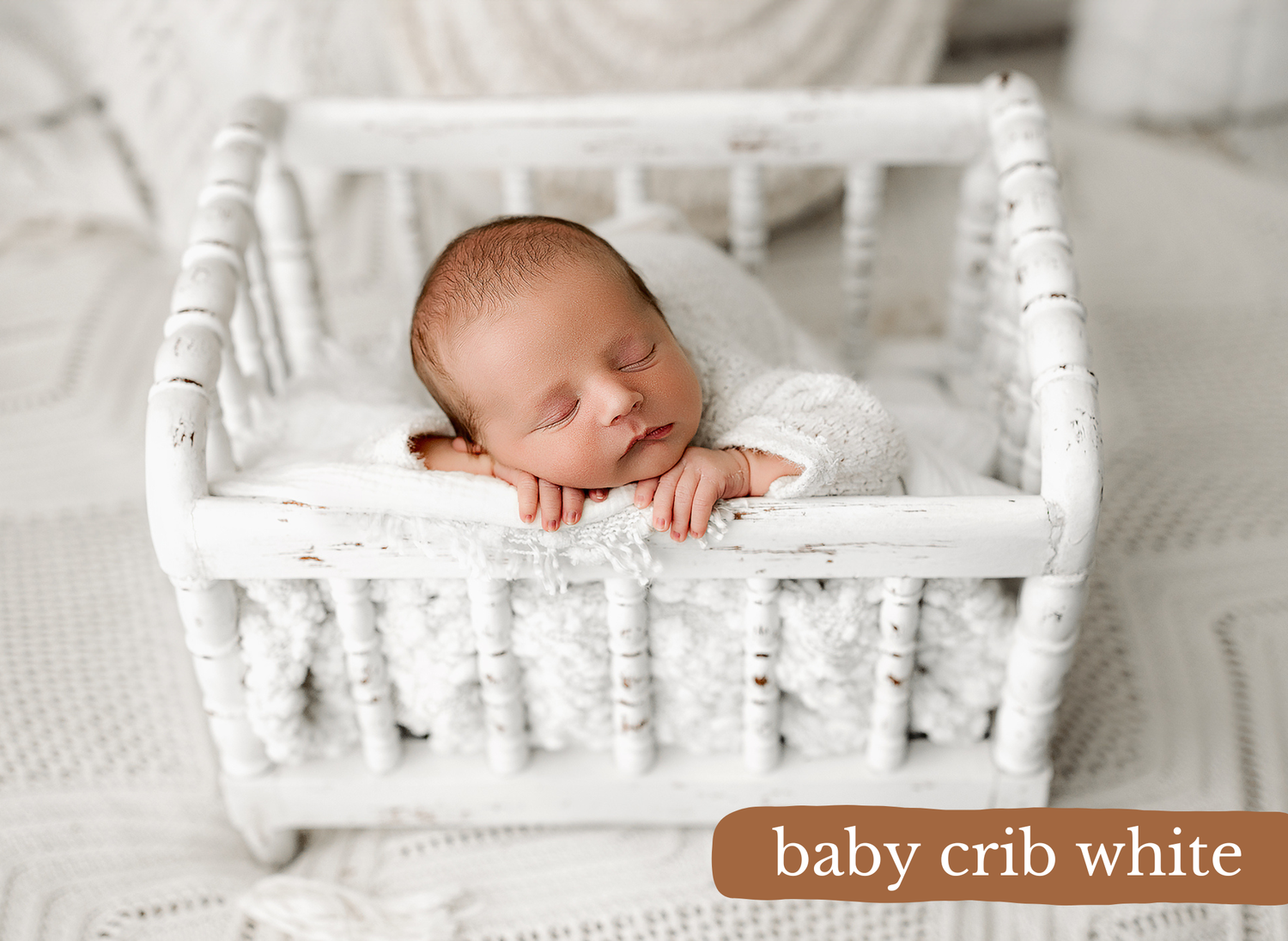 Small baby resting peacefully in a white wooden crib with elegant spindle details and soft bedding.