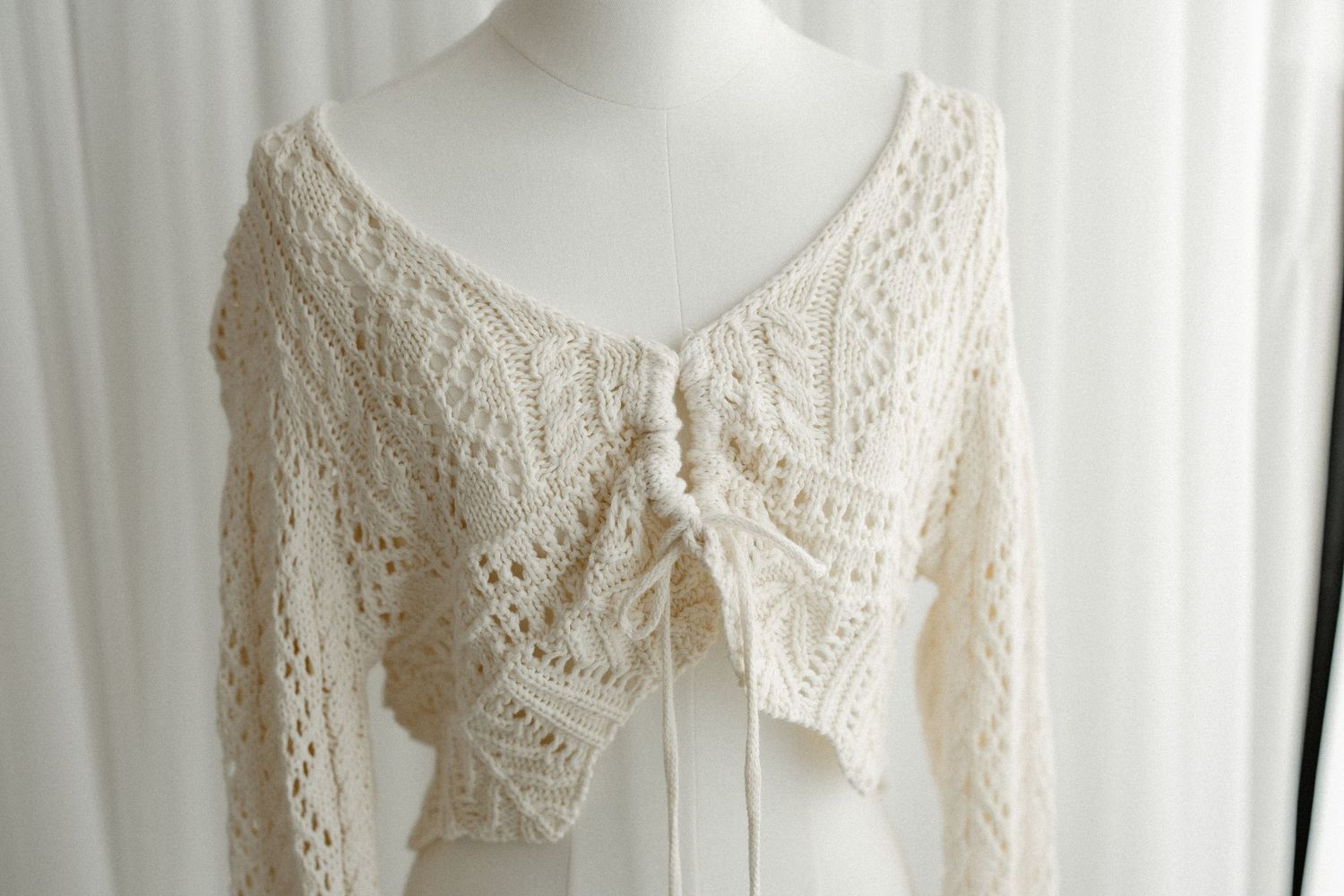 Close-up view of delicate vintage-style lace wedding dresses hanging on display with intricate embroidered details.