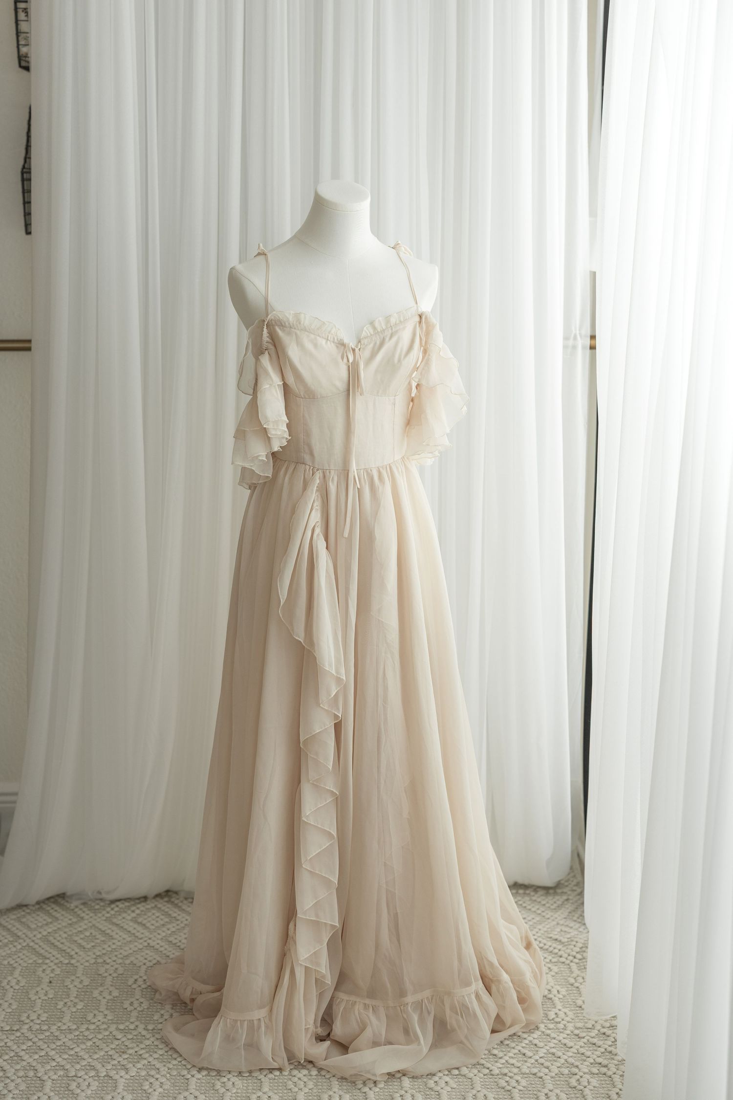 Romantic sheer cream-colored vintage-style nightgown with ruffled details and flowing fabric displayed on a mannequin.