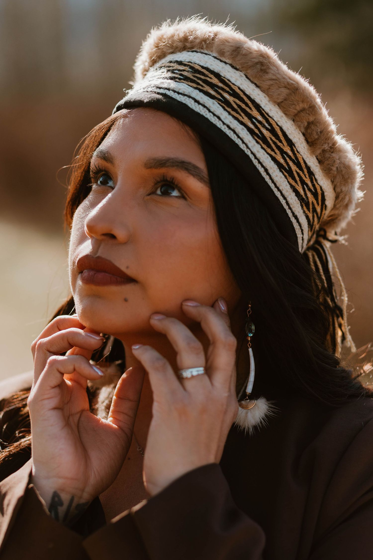 Close-up golden hour portrait showing woman in winter headband with rings and natural warm lighting.