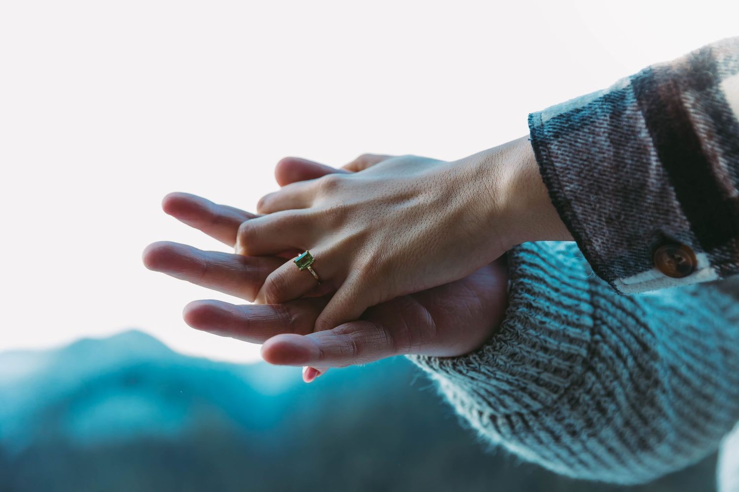 Close-up of hand wearing knit sleeve against blue background.