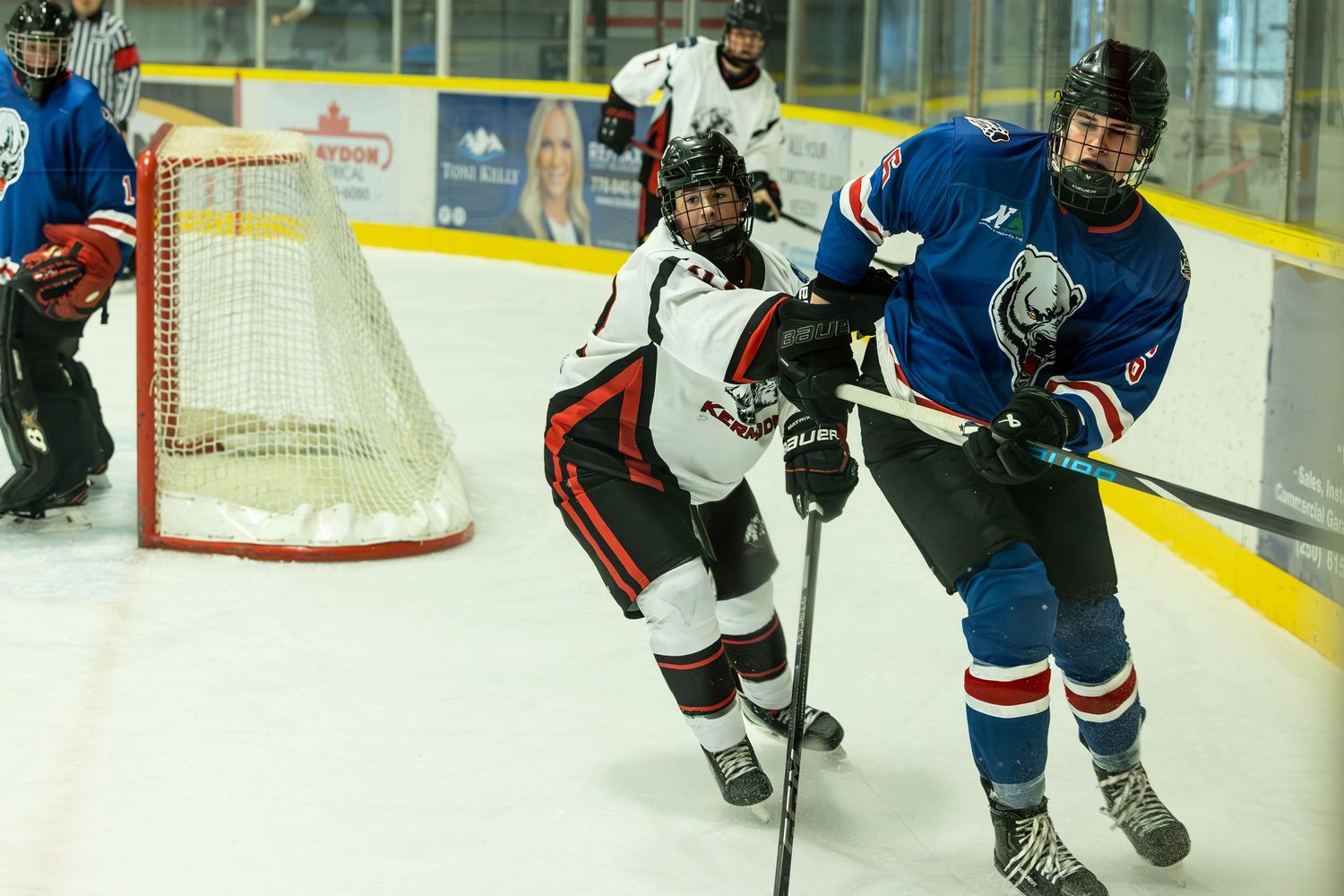 Hockey players from opposing teams battle for position near the goal during competitive match.