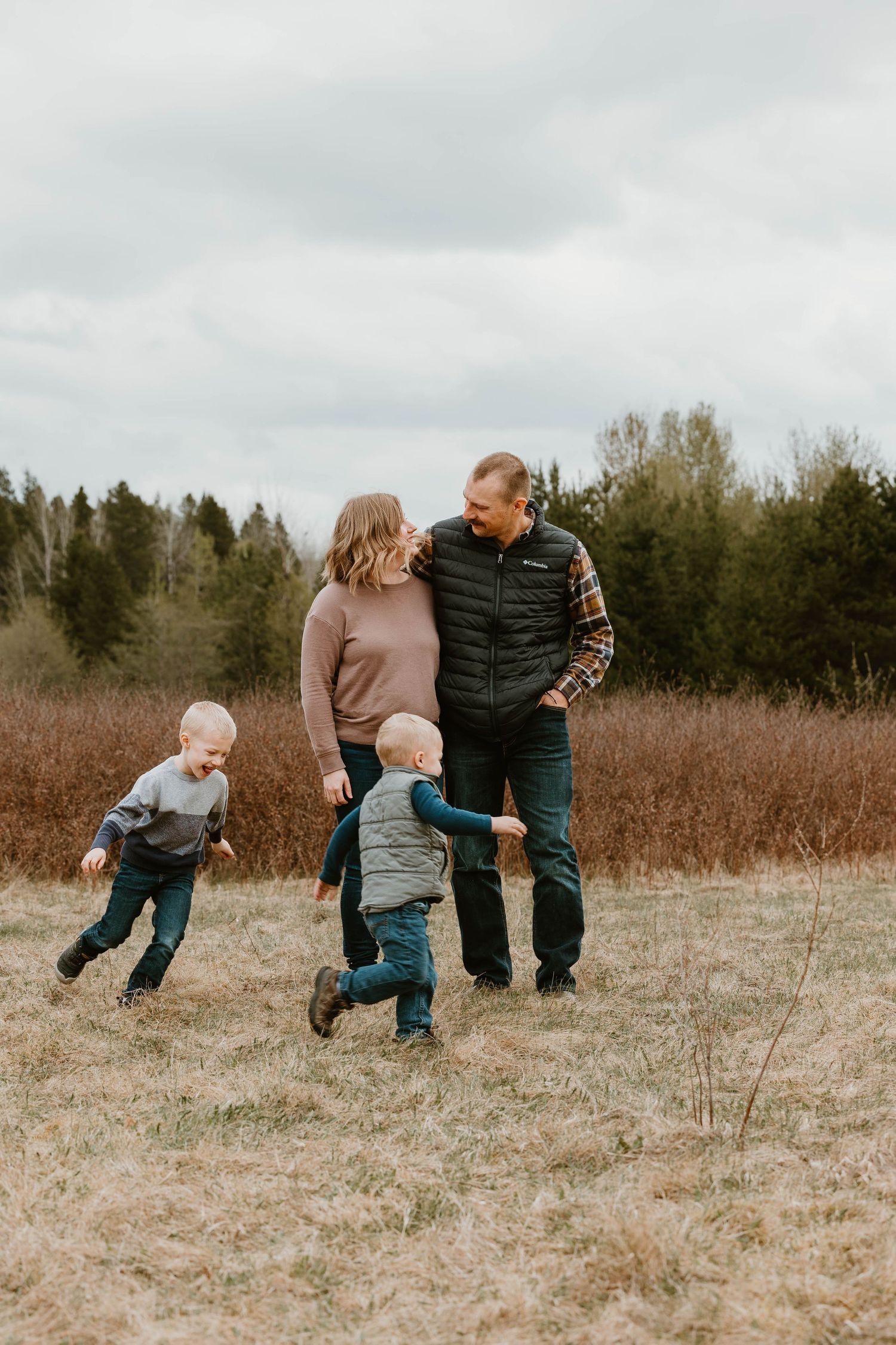 Family walking together in field while children run and play.