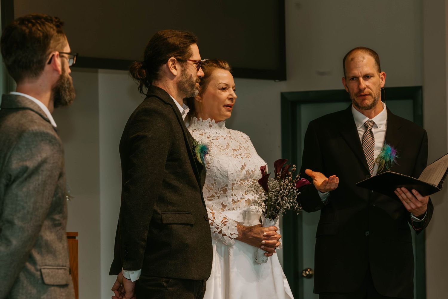 A wedding ceremony takes place inside a church with attendants gathered at the altar.