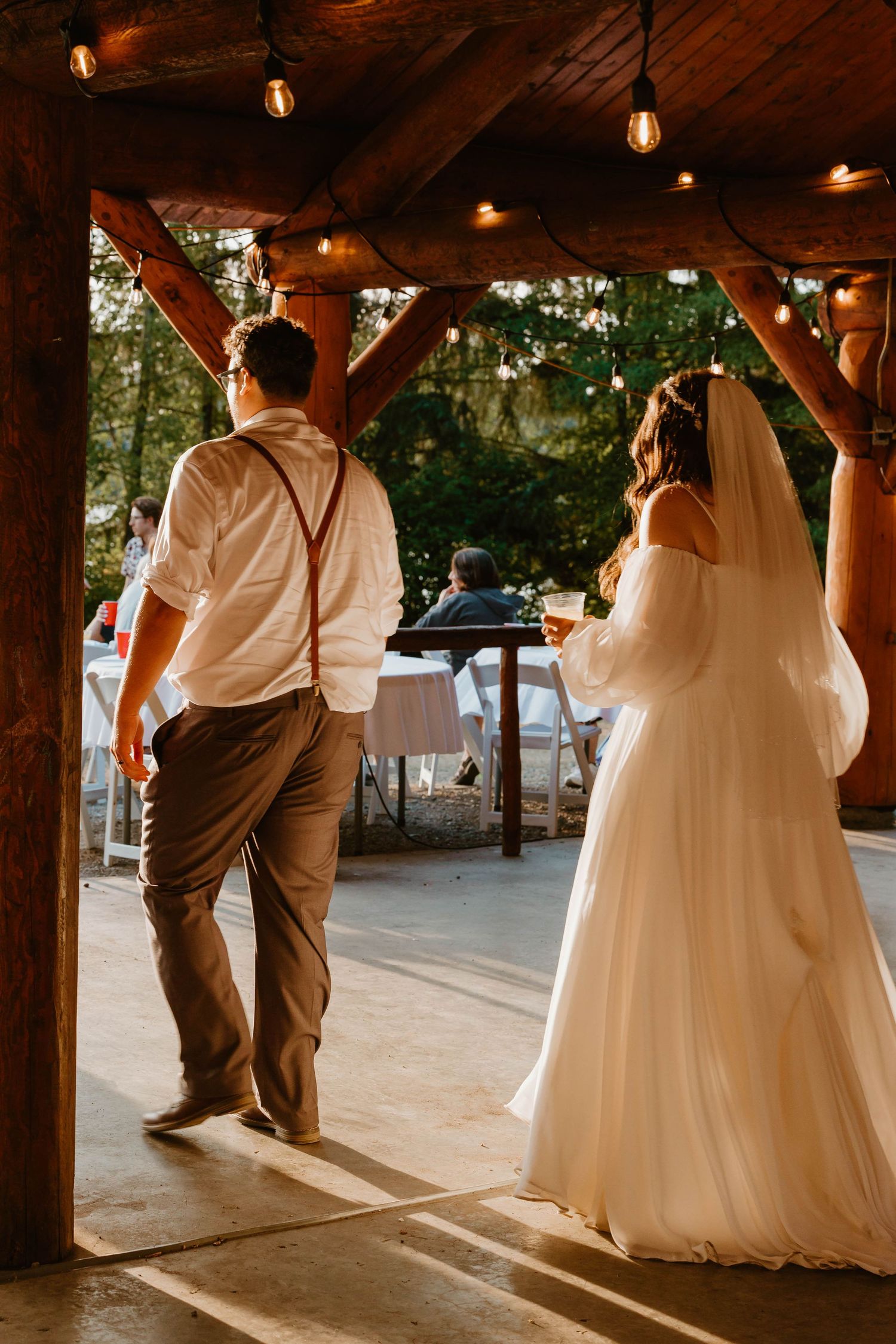 A wedding ceremony in a rustic wooden pavilion with string lights overhead.