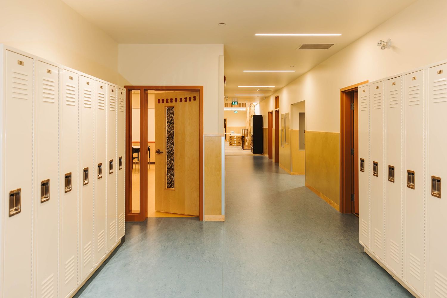 School hallway with white lockers and two-tone walls in neutral colors.