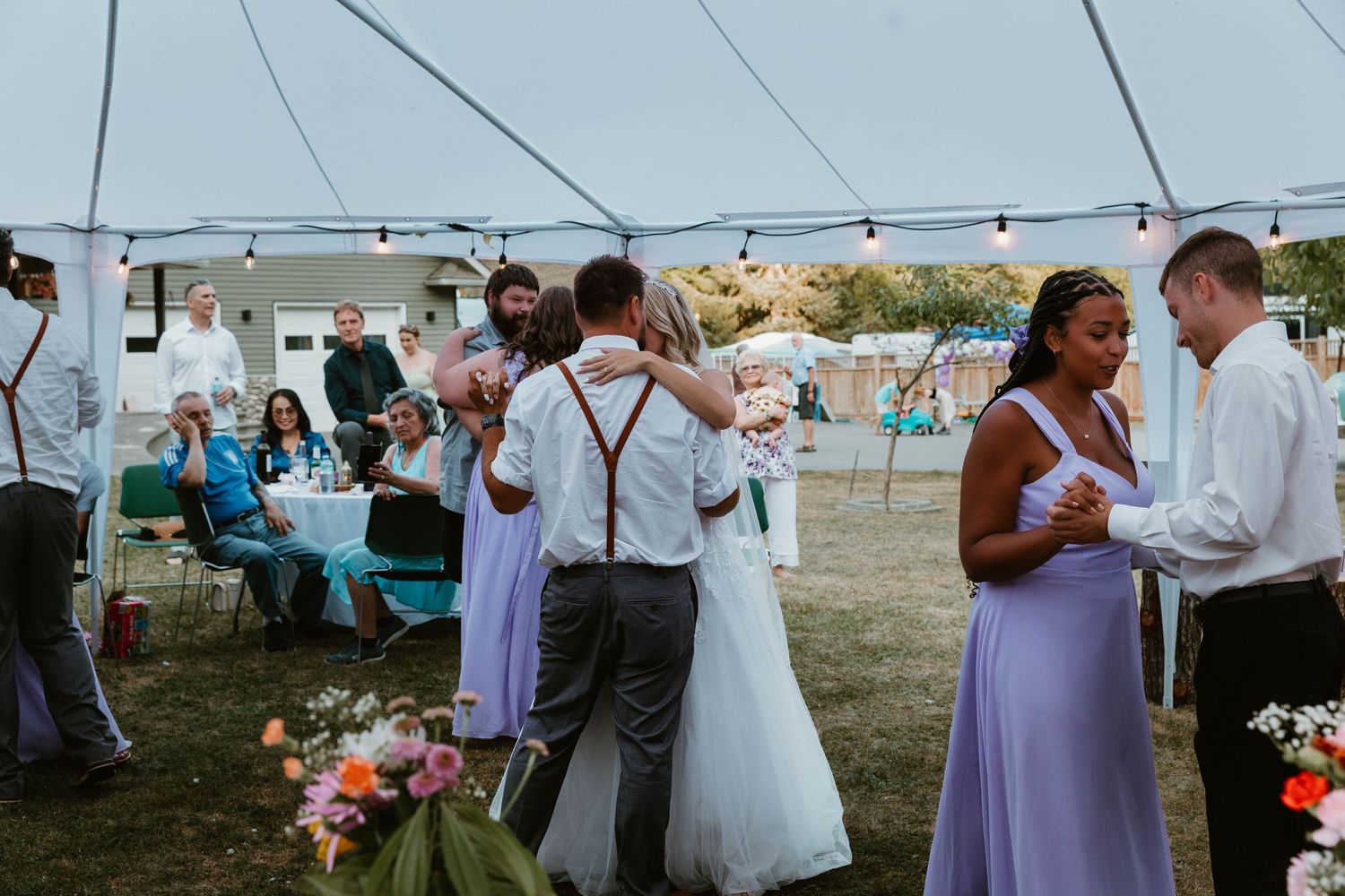 Wedding reception under white tent with guests dancing and mingling.
