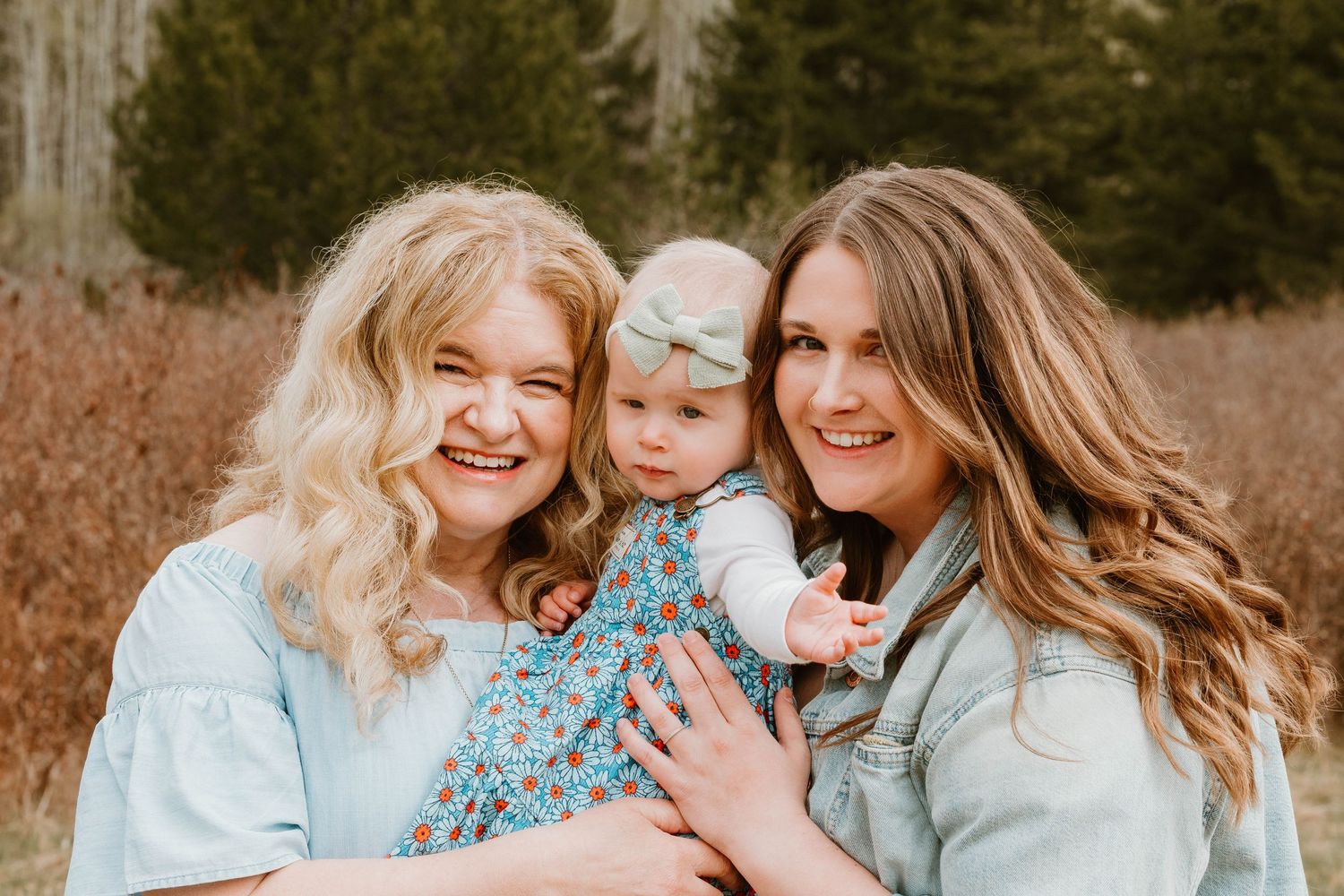 Three people share a joyful moment together outdoors in coordinating blue outfits.
