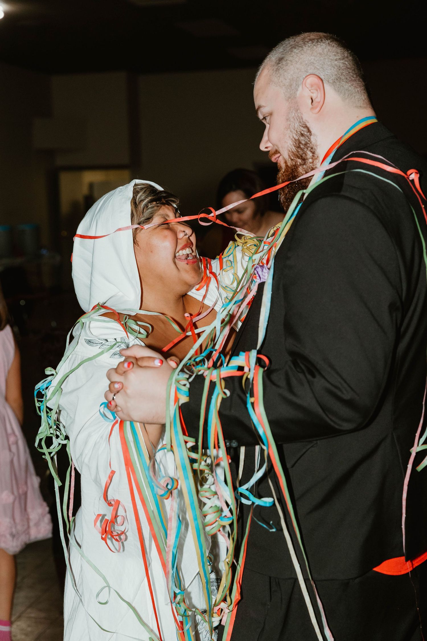 A couple sharing a joyful moment with colorful streamers at a celebration.