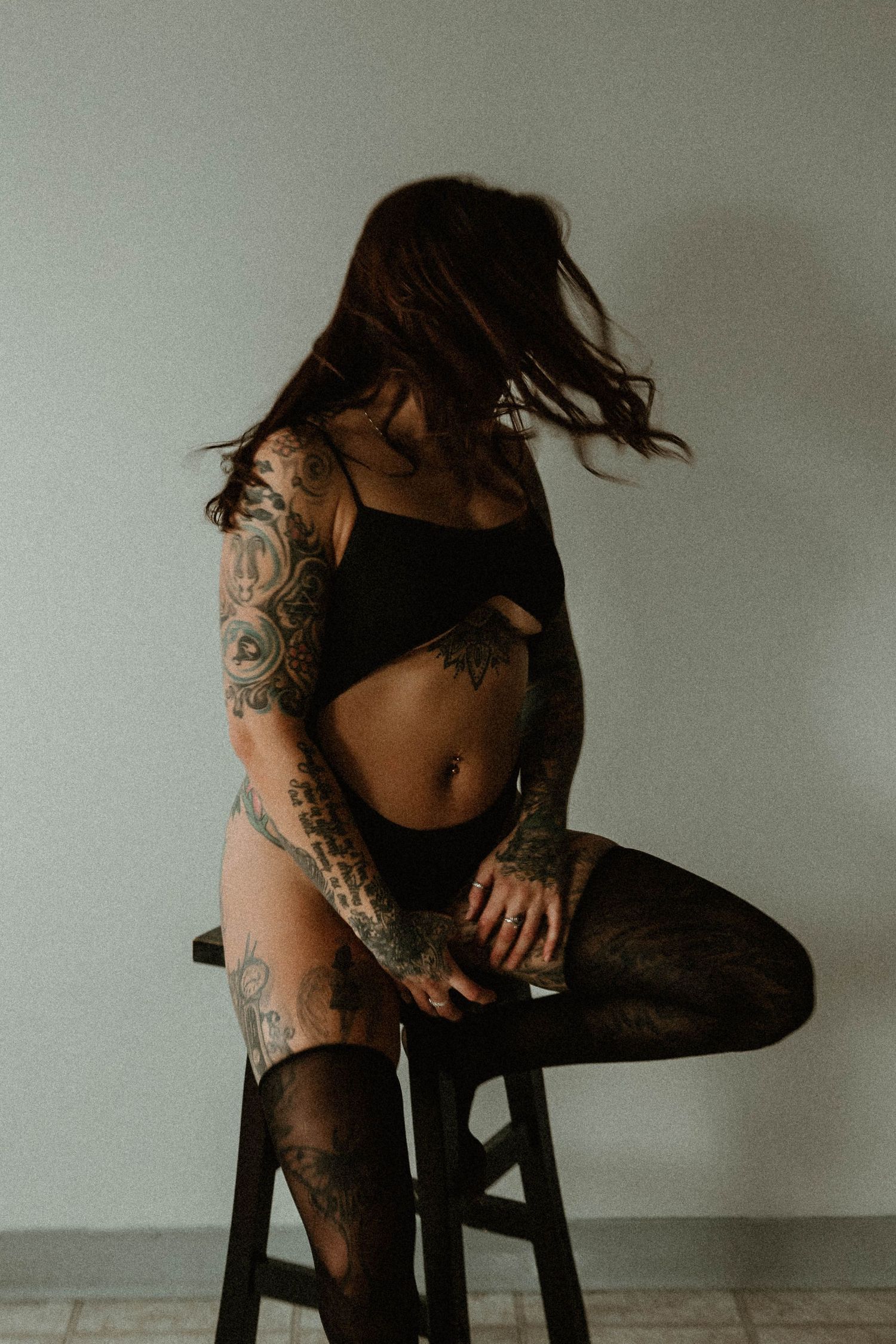 Moody portrait showing intricate tattoo artwork on person in black outfit.