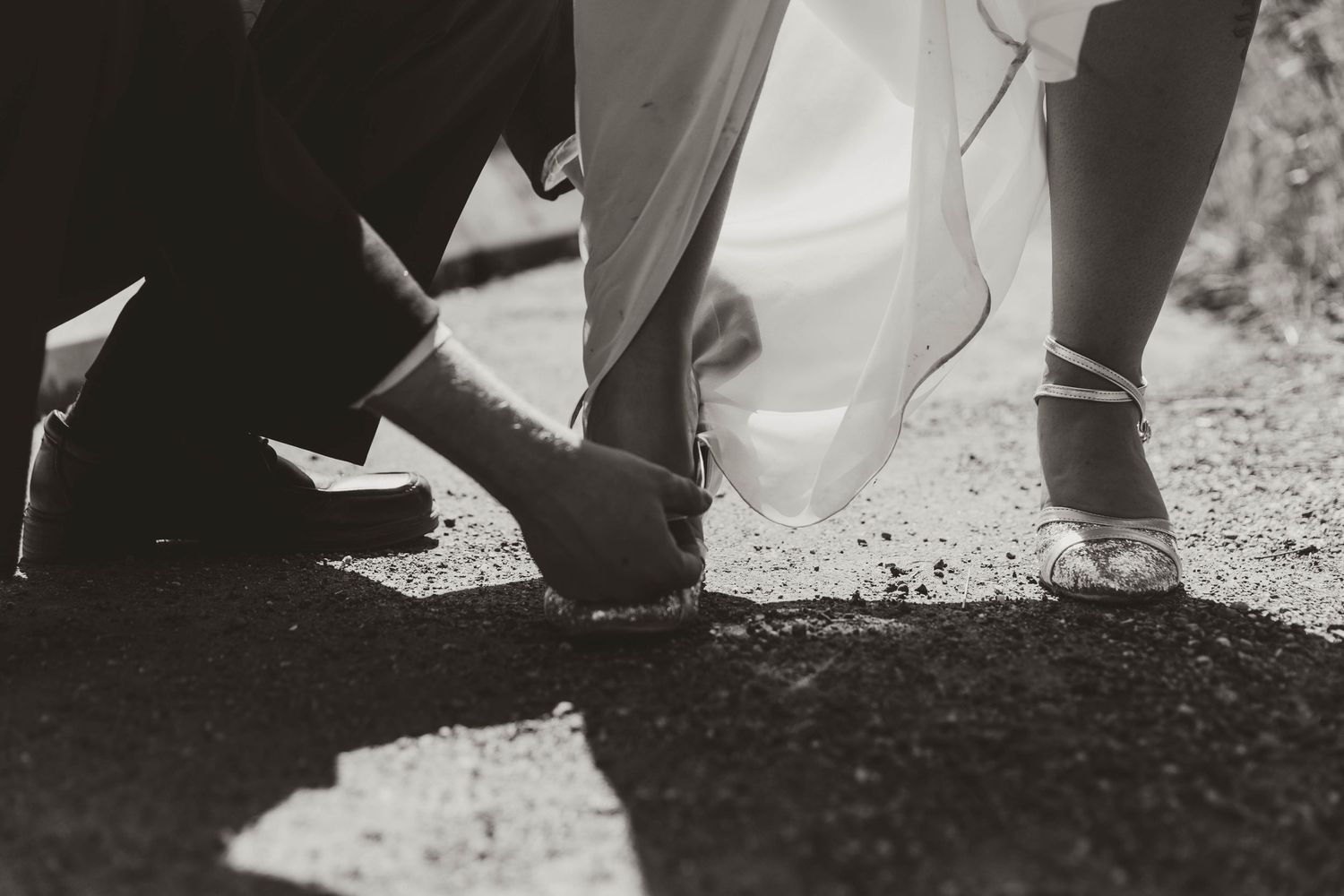 Black and white detail shot of shoes during an outdoor wedding ceremony.