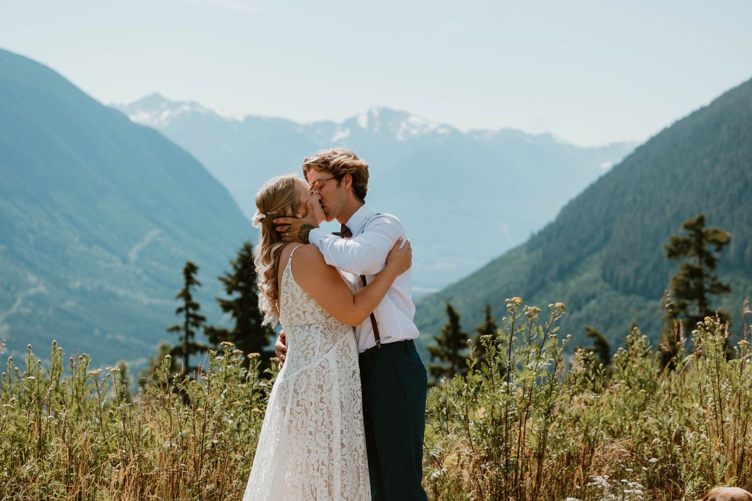Newlyweds share intimate moment with mountain landscape backdrop during outdoor ceremony.