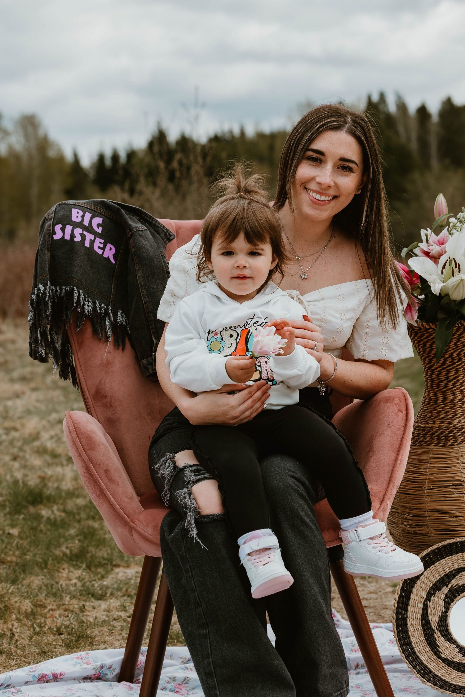 A cozy outdoor portrait session in a pink chair with 'Big Sister' denim jacket detail.